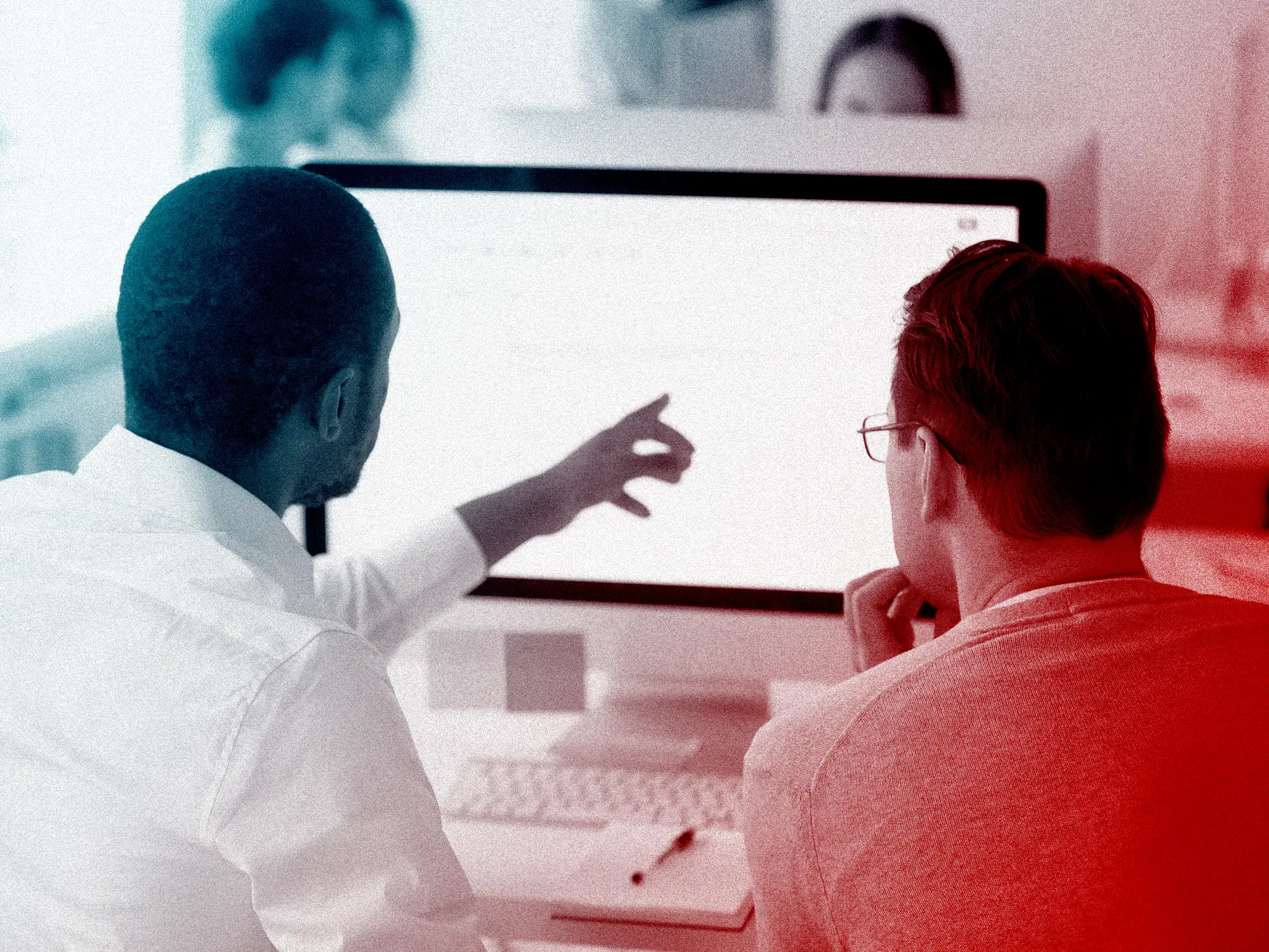 A manager pointing and looking at a computer screen with an employee