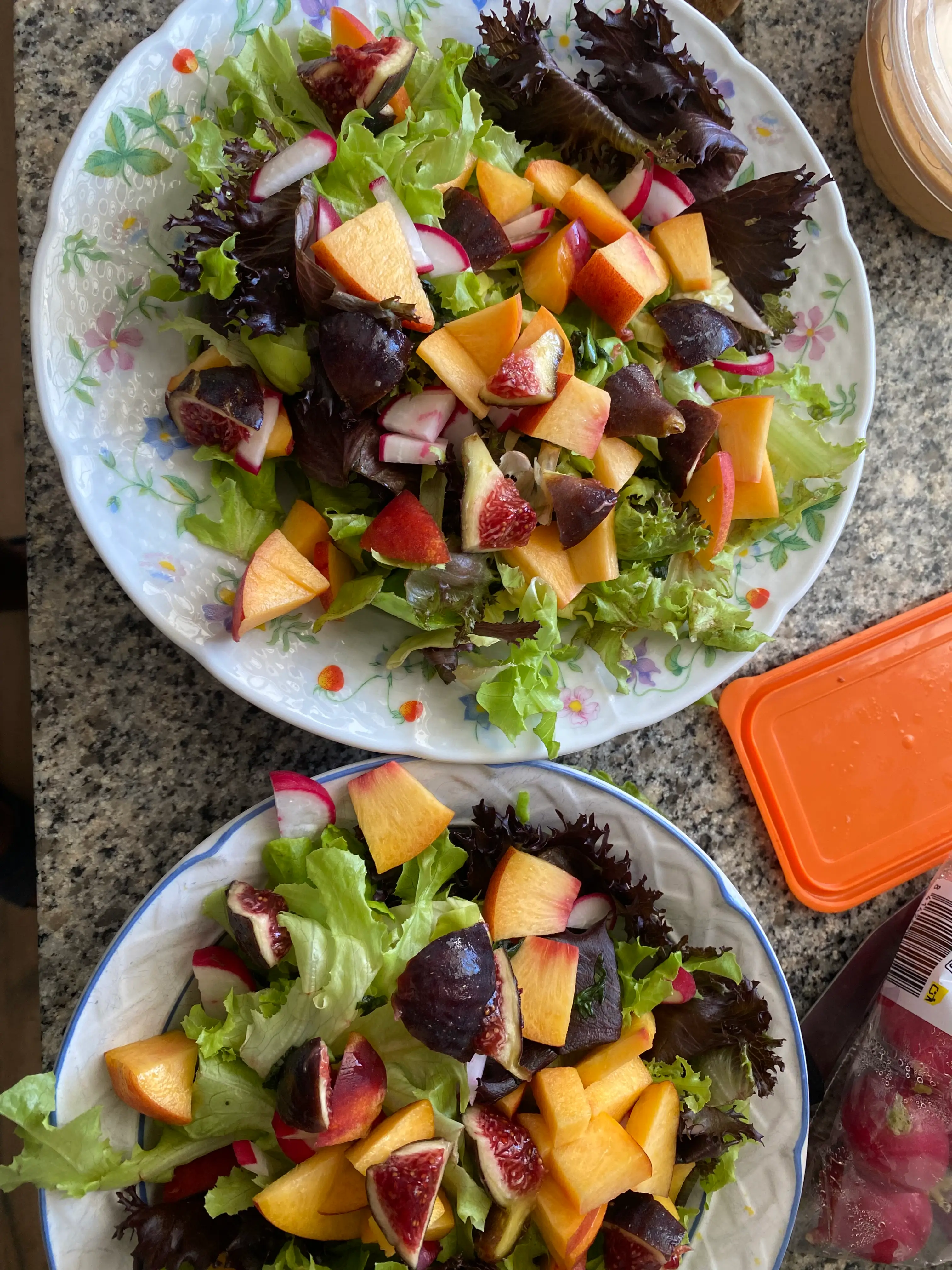 Two salads topped with fruit, dressing