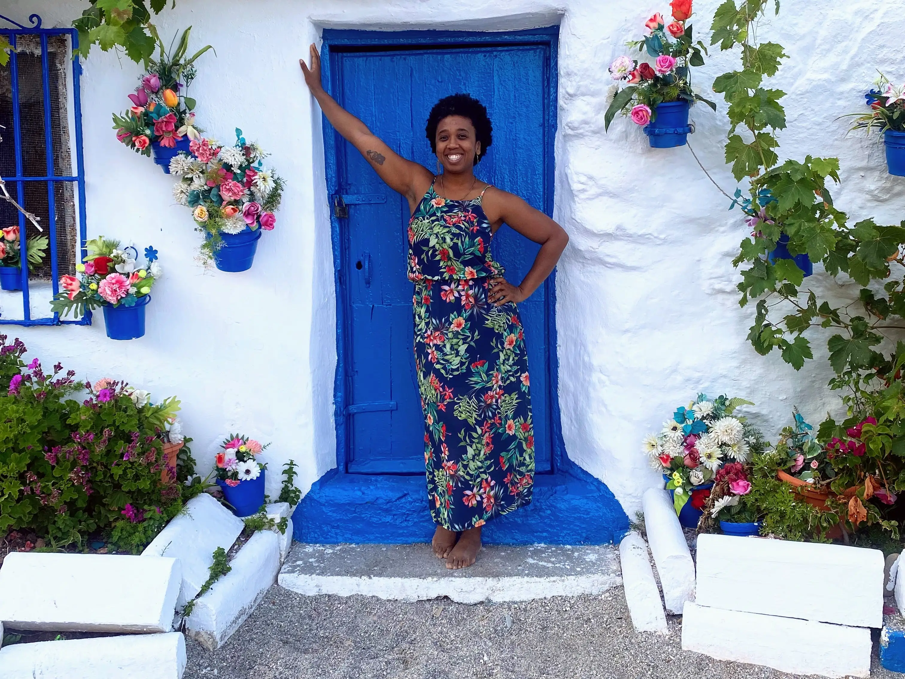 Woman smiling, posing in front of blue door on white building