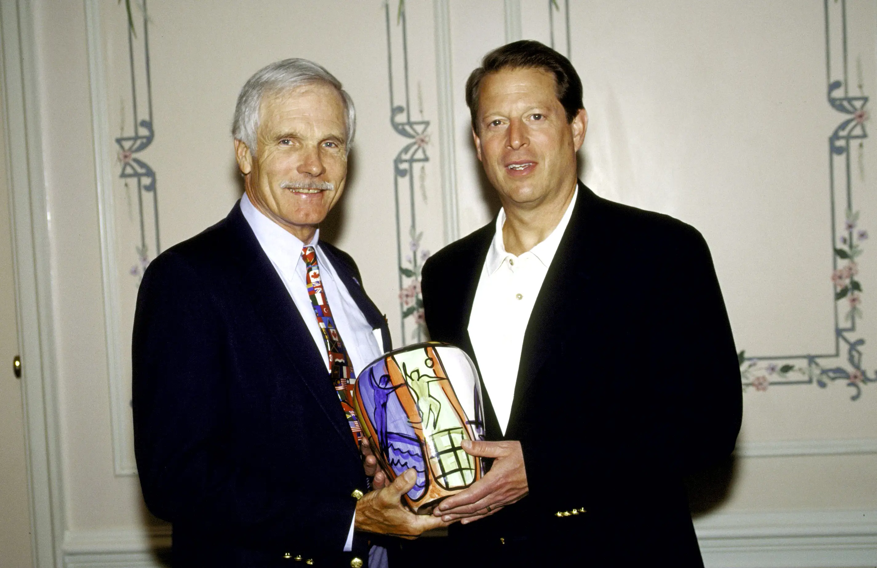 Ted Turner and Al Gore hold a trophy together in 1986.