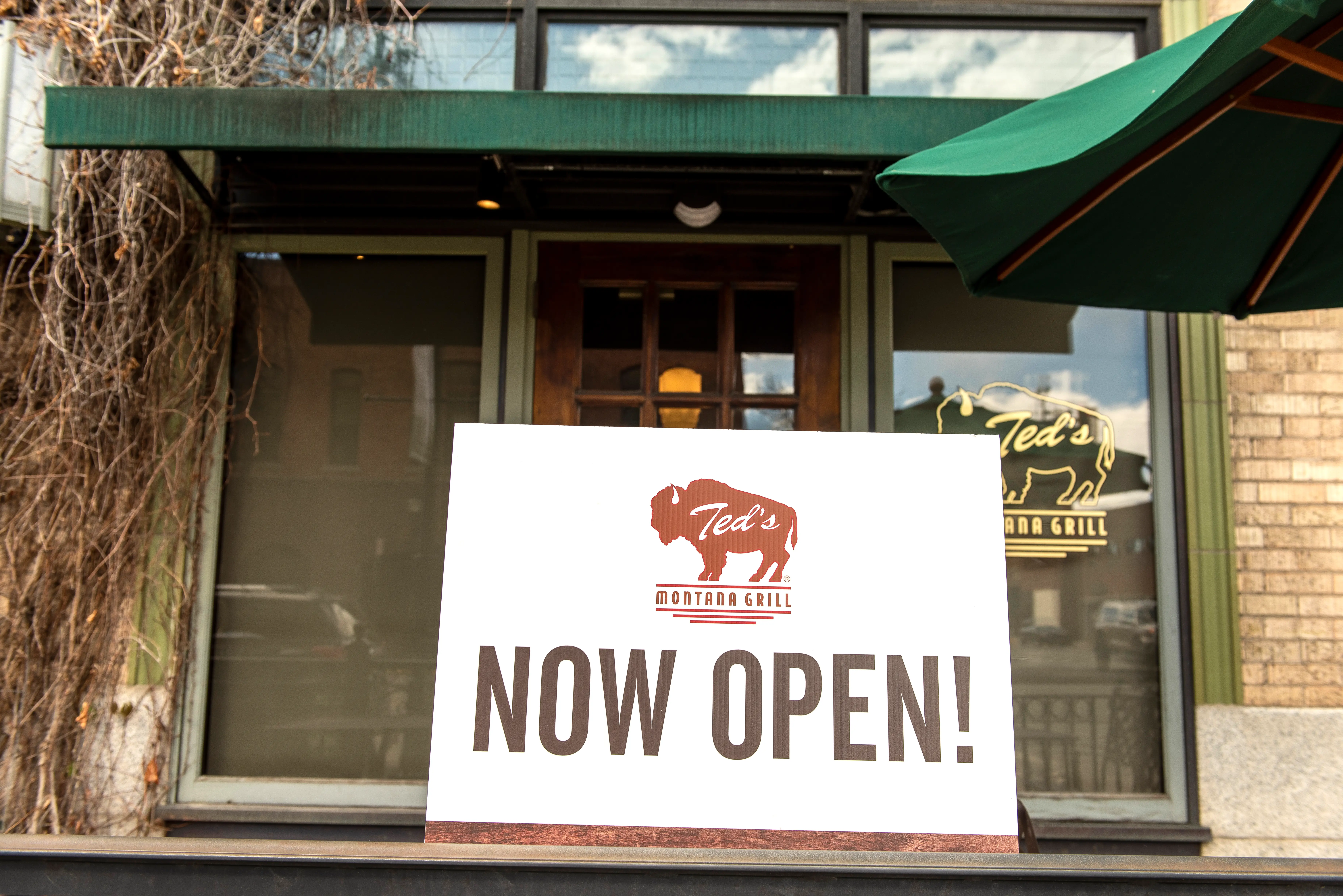 A sign outside a Ted's Montana Grill reads 'Now Open!'