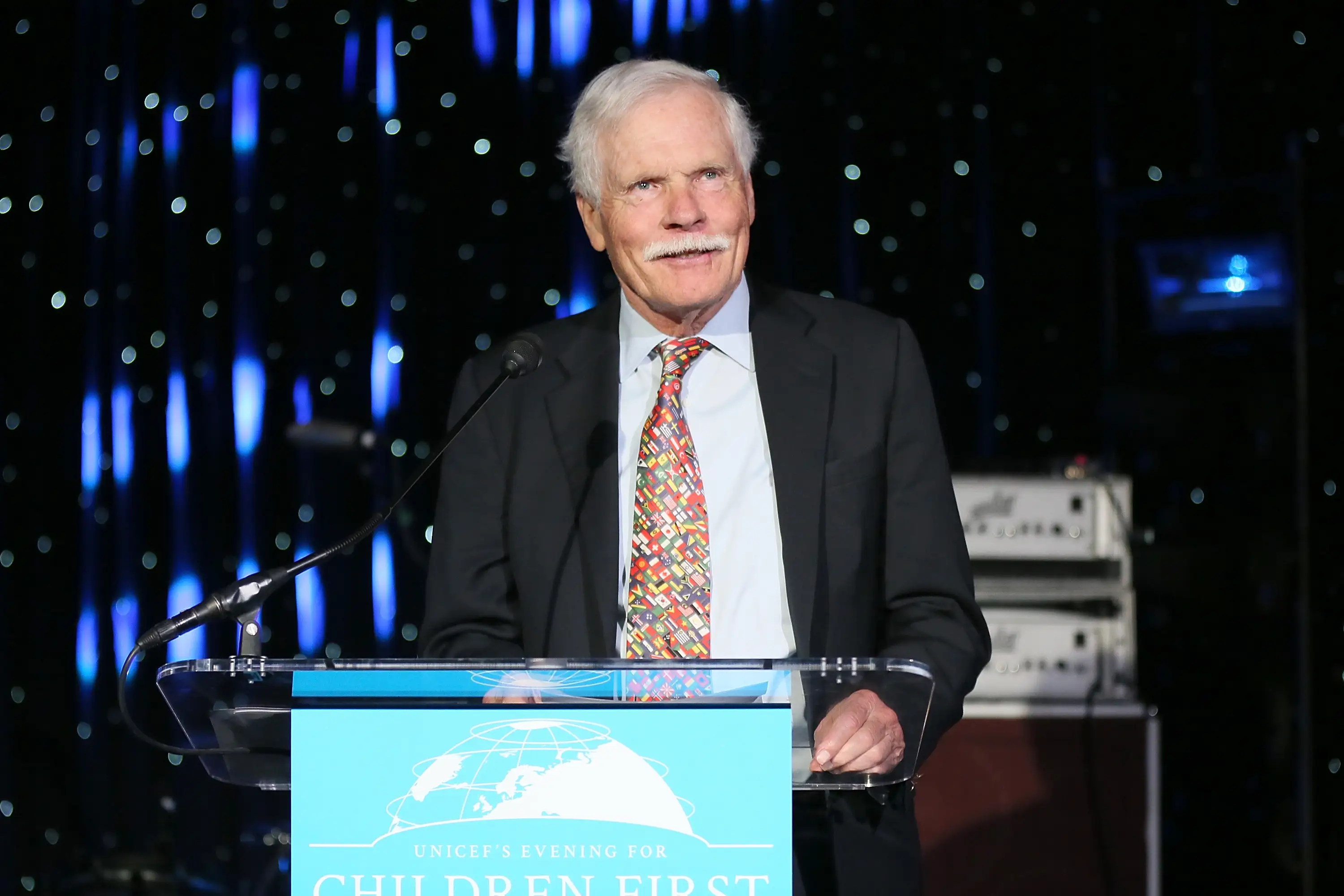 Ted Turner speaks at a lectern during a UNICEF event.