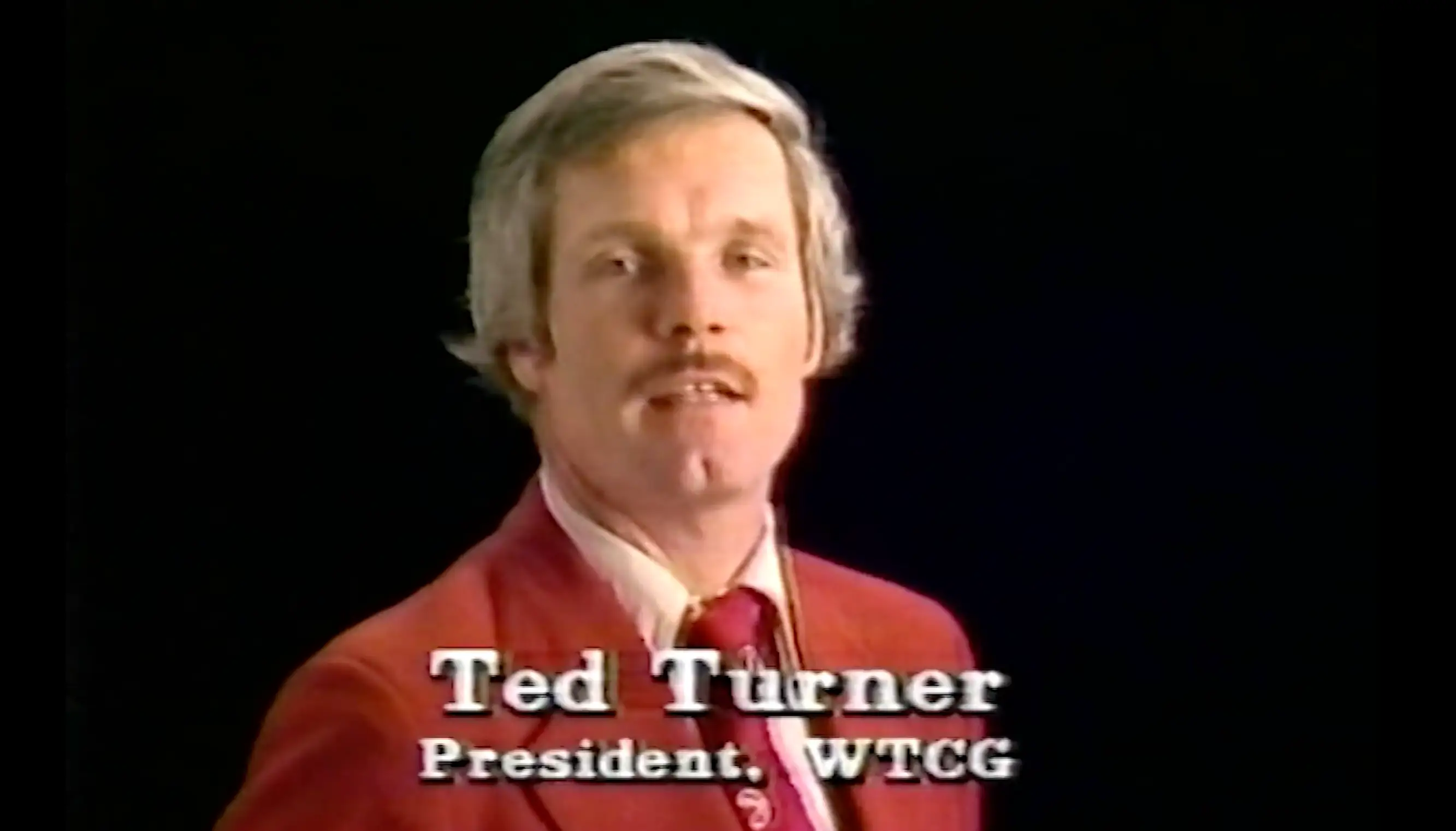 Ted Turner, dressed in a red suit, in a WTCG advertisement.