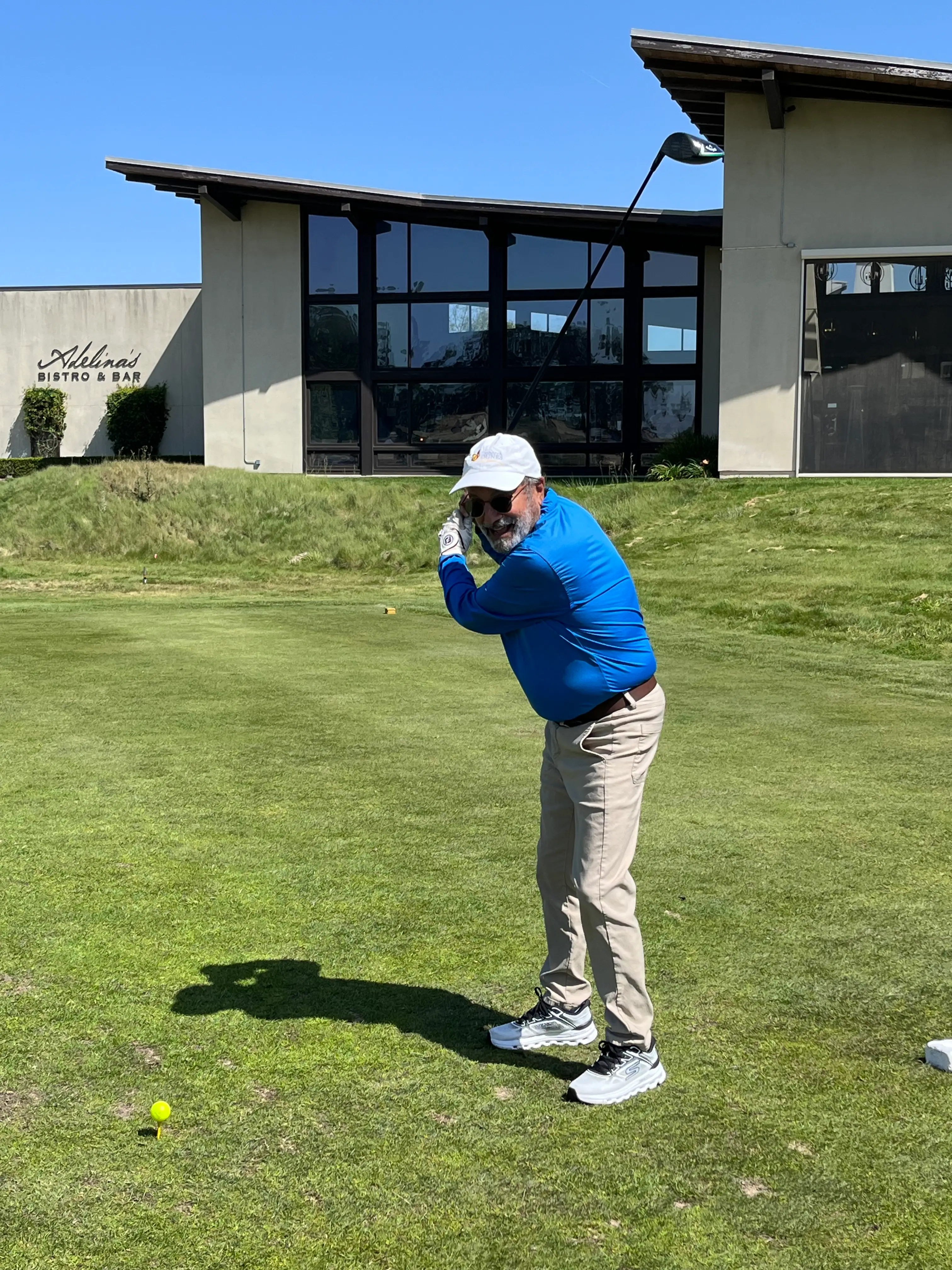 The author's husband swings a golf club.