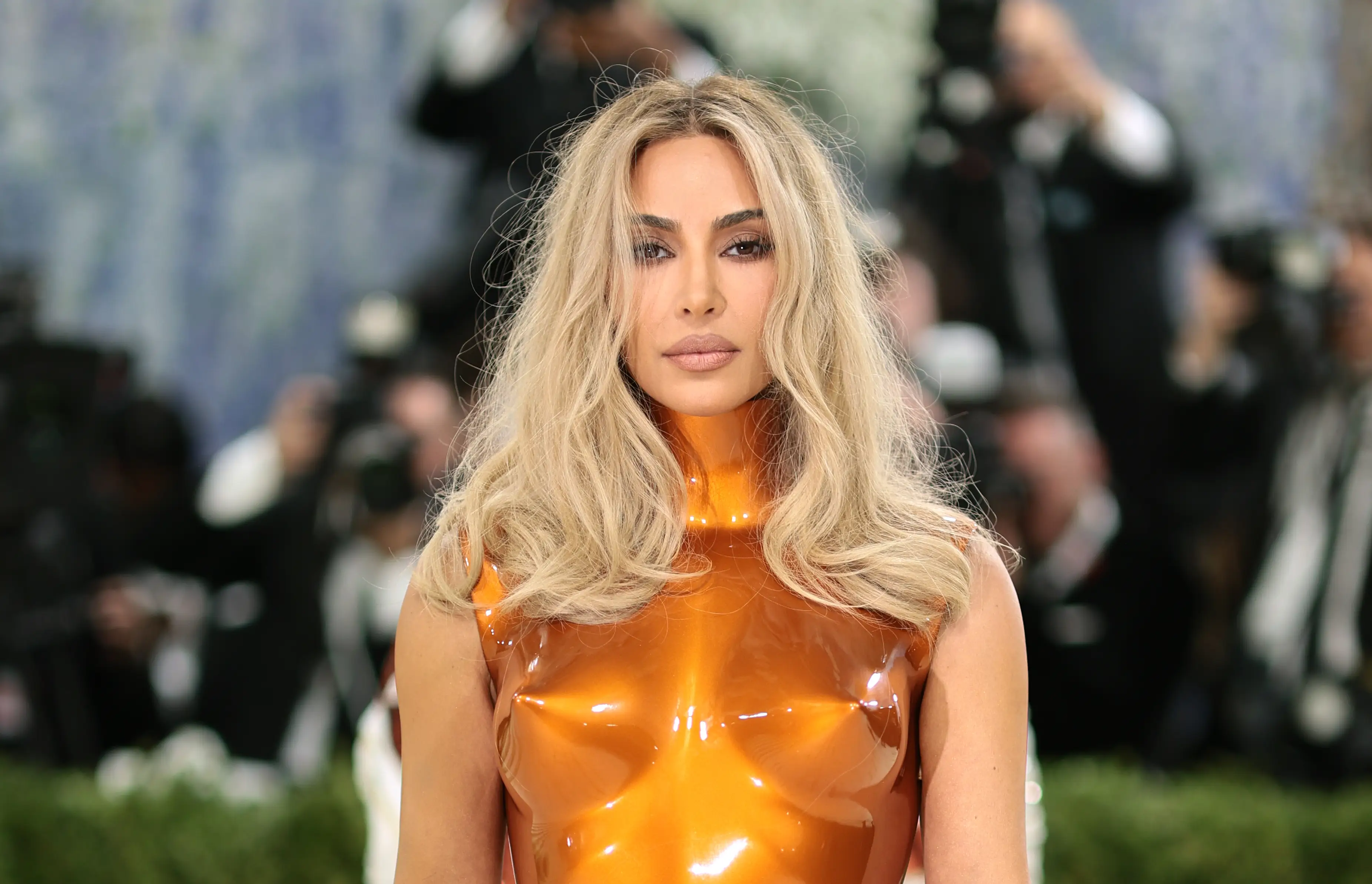 Kim Kardashian poses at the 2026 Met Gala in an orange outfit.