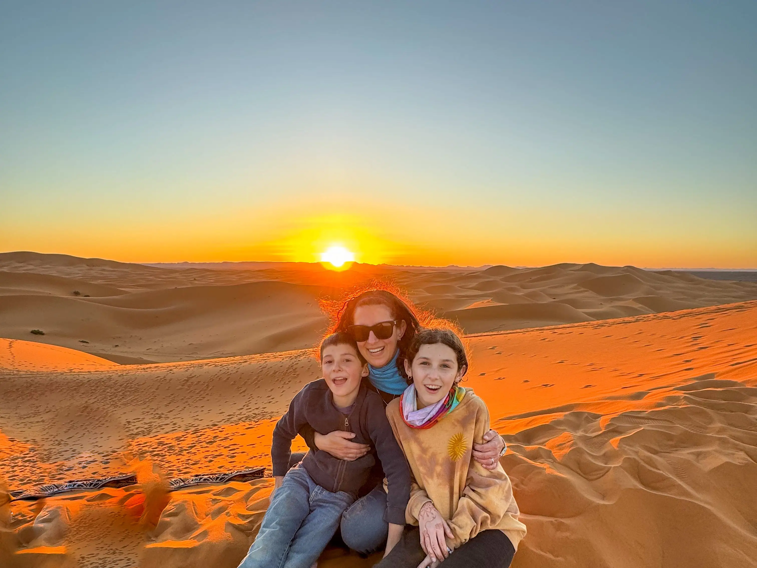 Jamie poses with her kids in the desert at sunset.