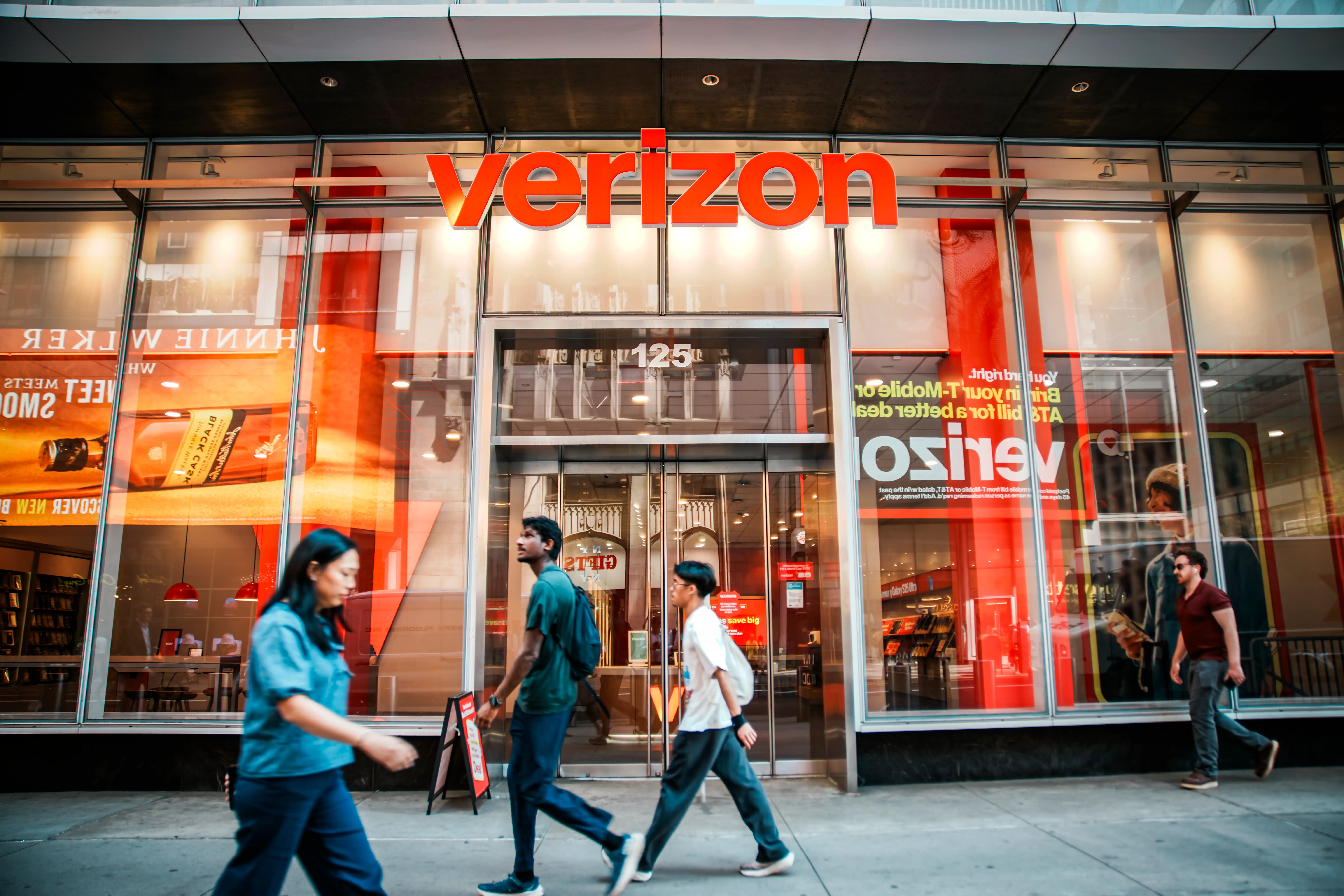 People walk in front of a Verizon store on April 17, 2026 in New York City.