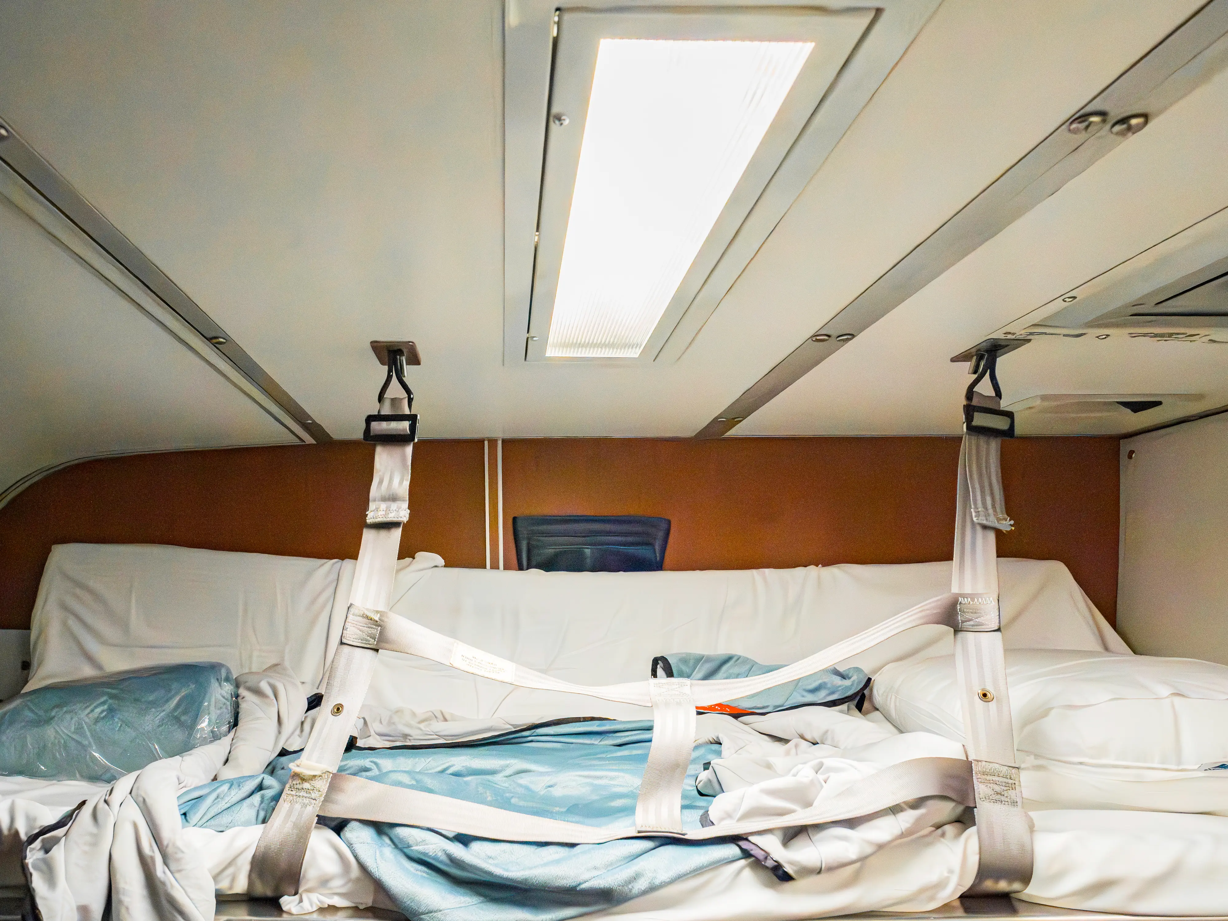 The top bunk in an Amtrak bedroom with blankets and pillows on top