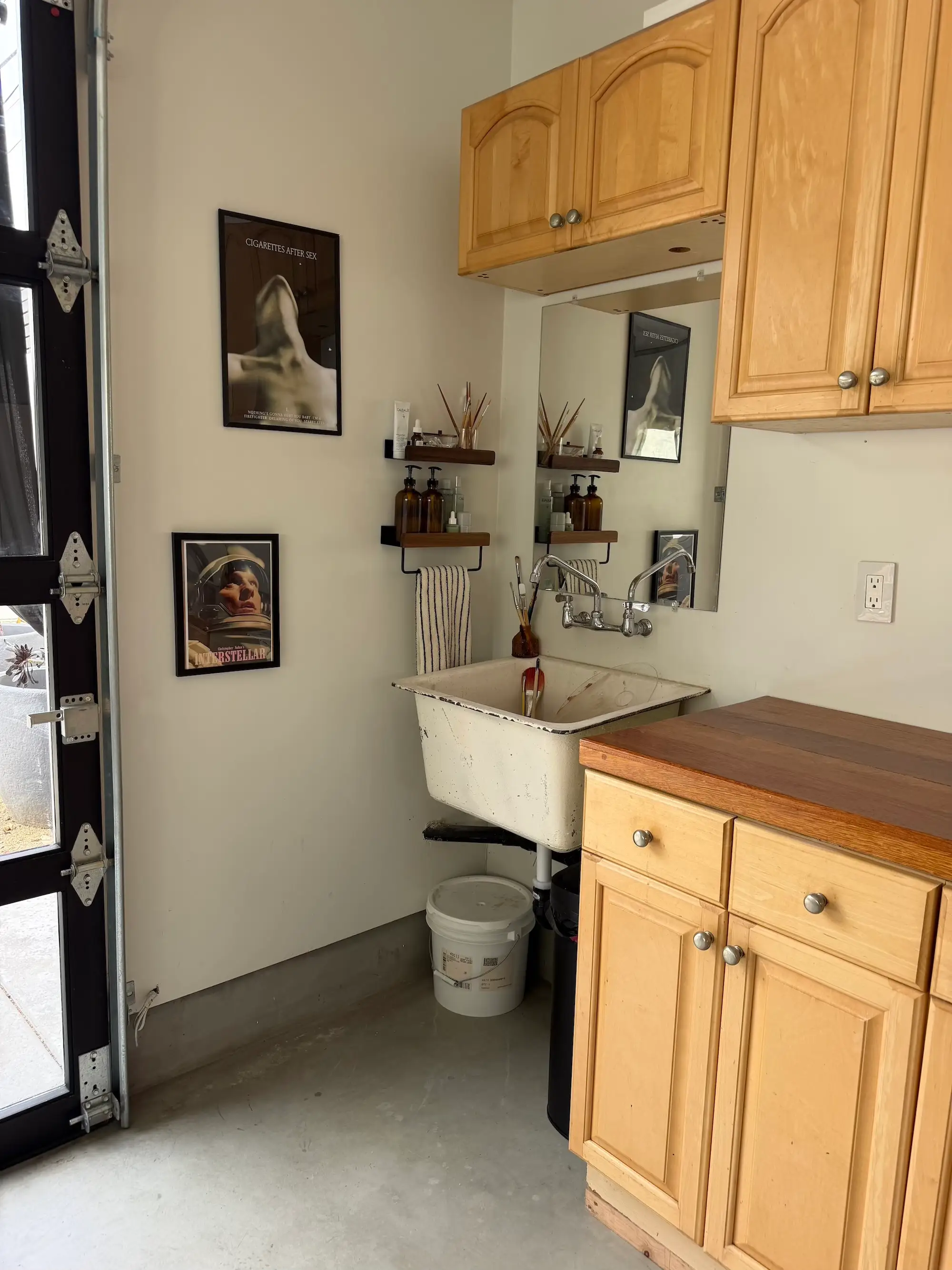 A sink and vanity next to cabinetry with artwork on the wall.