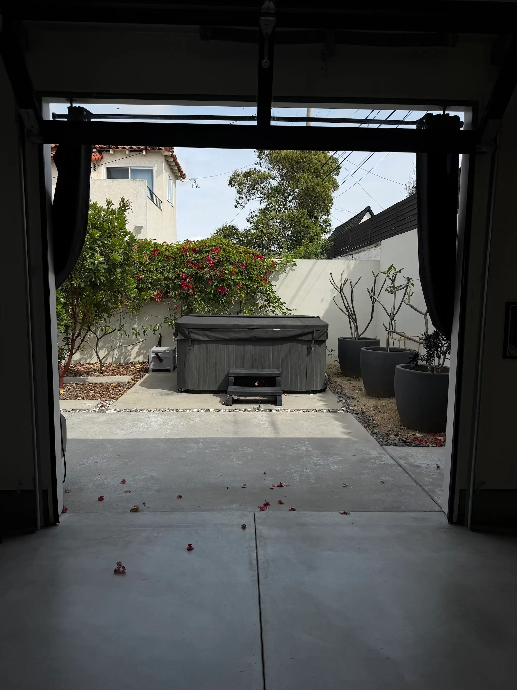 An open garage with a patio in front of it. A jacuzzi sits on the patio.