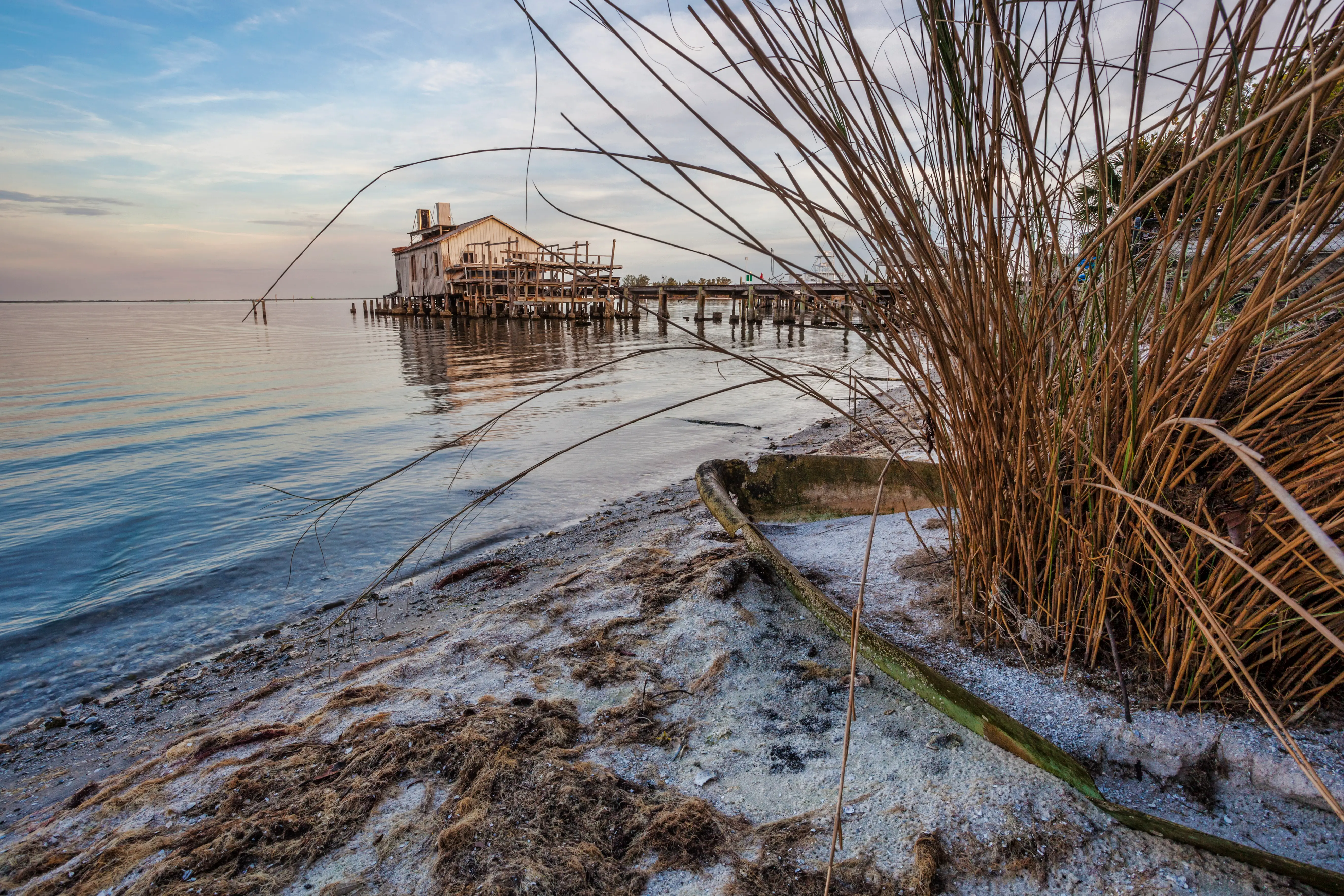 A doc, with an old home and bridge, sits on water.