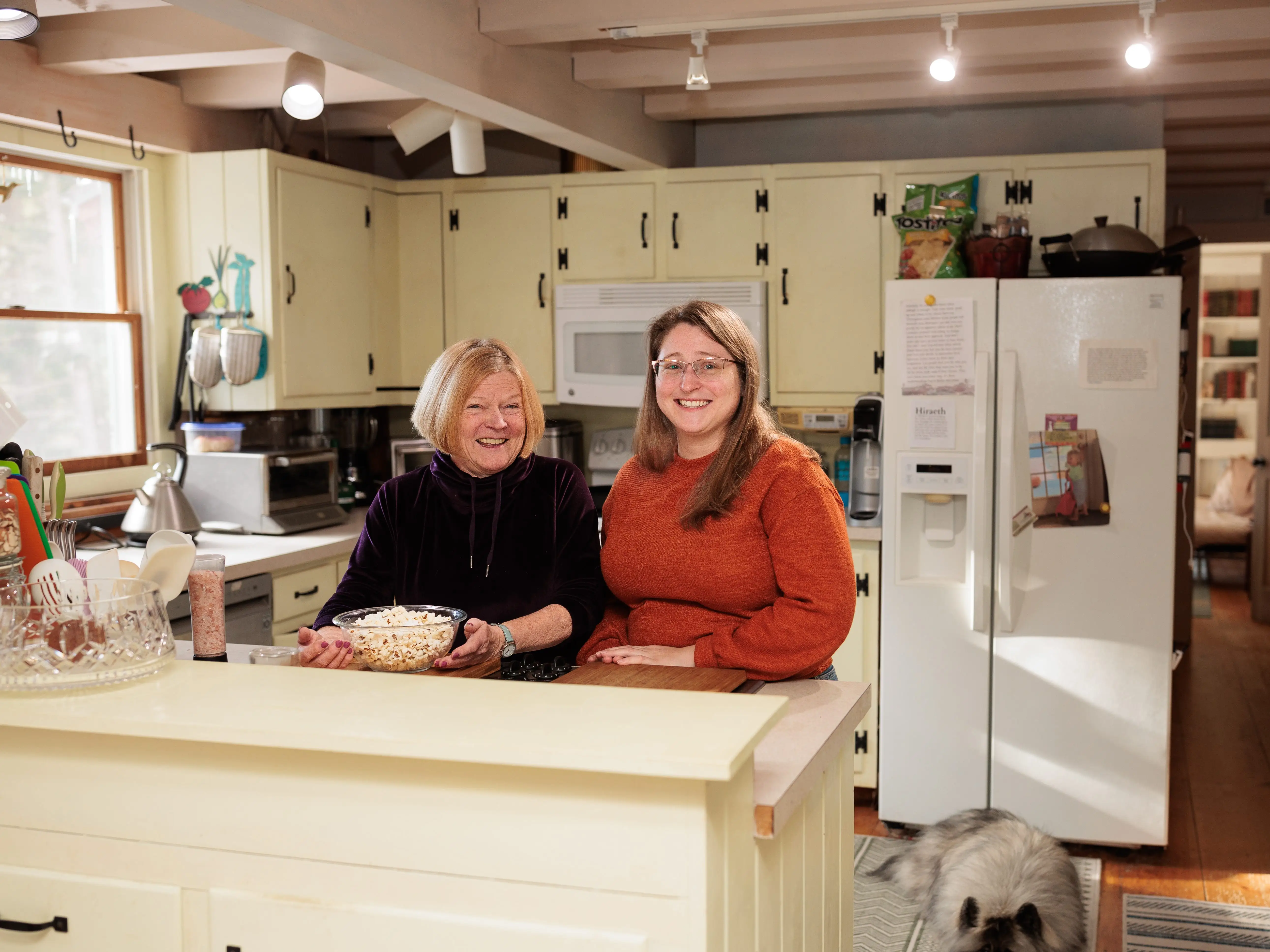An older woman and a younger woman are standing in a kitchen.