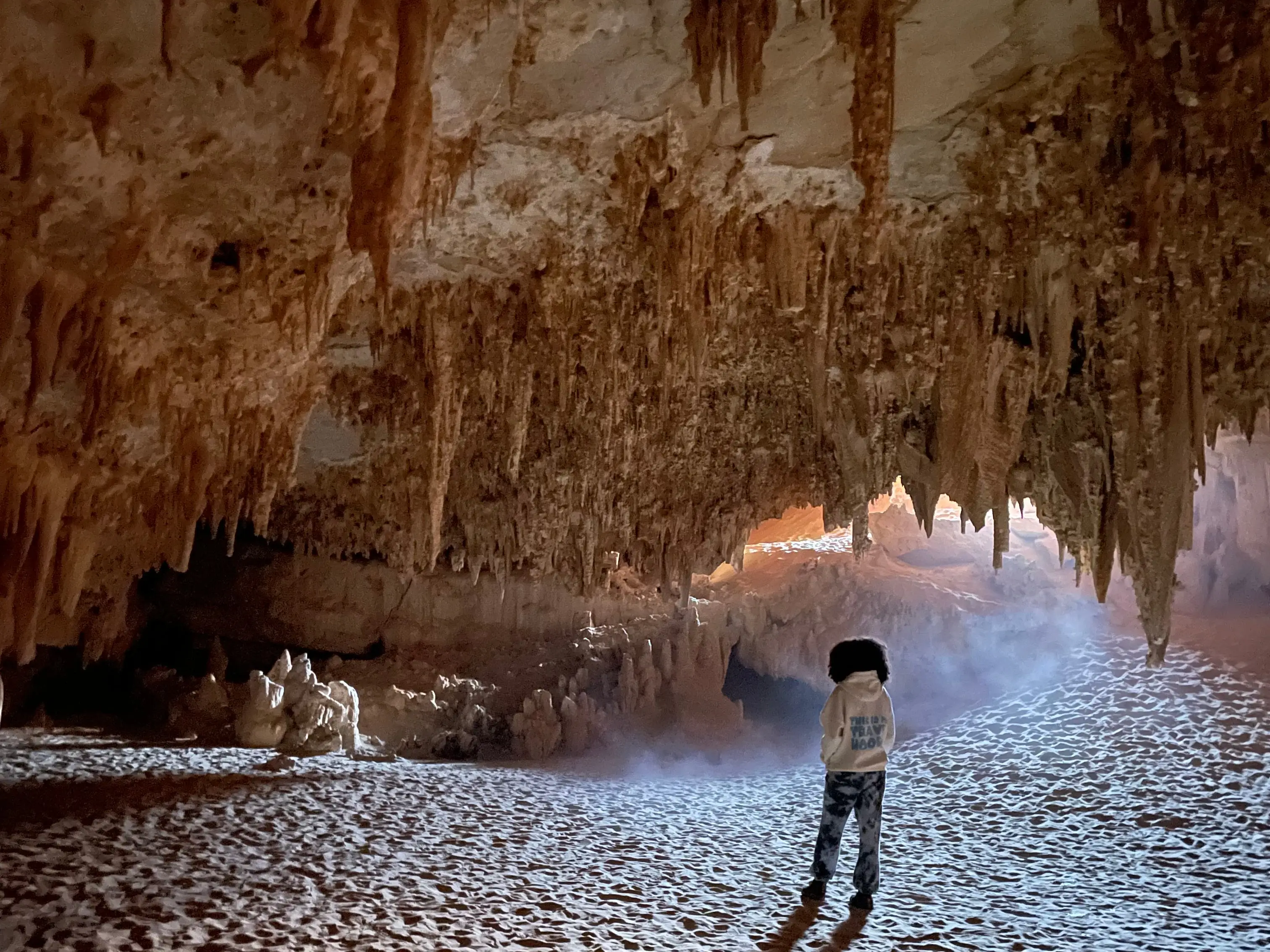 A woman walking around Egypt's Djara Cave, which is full of dripstone rock formations.