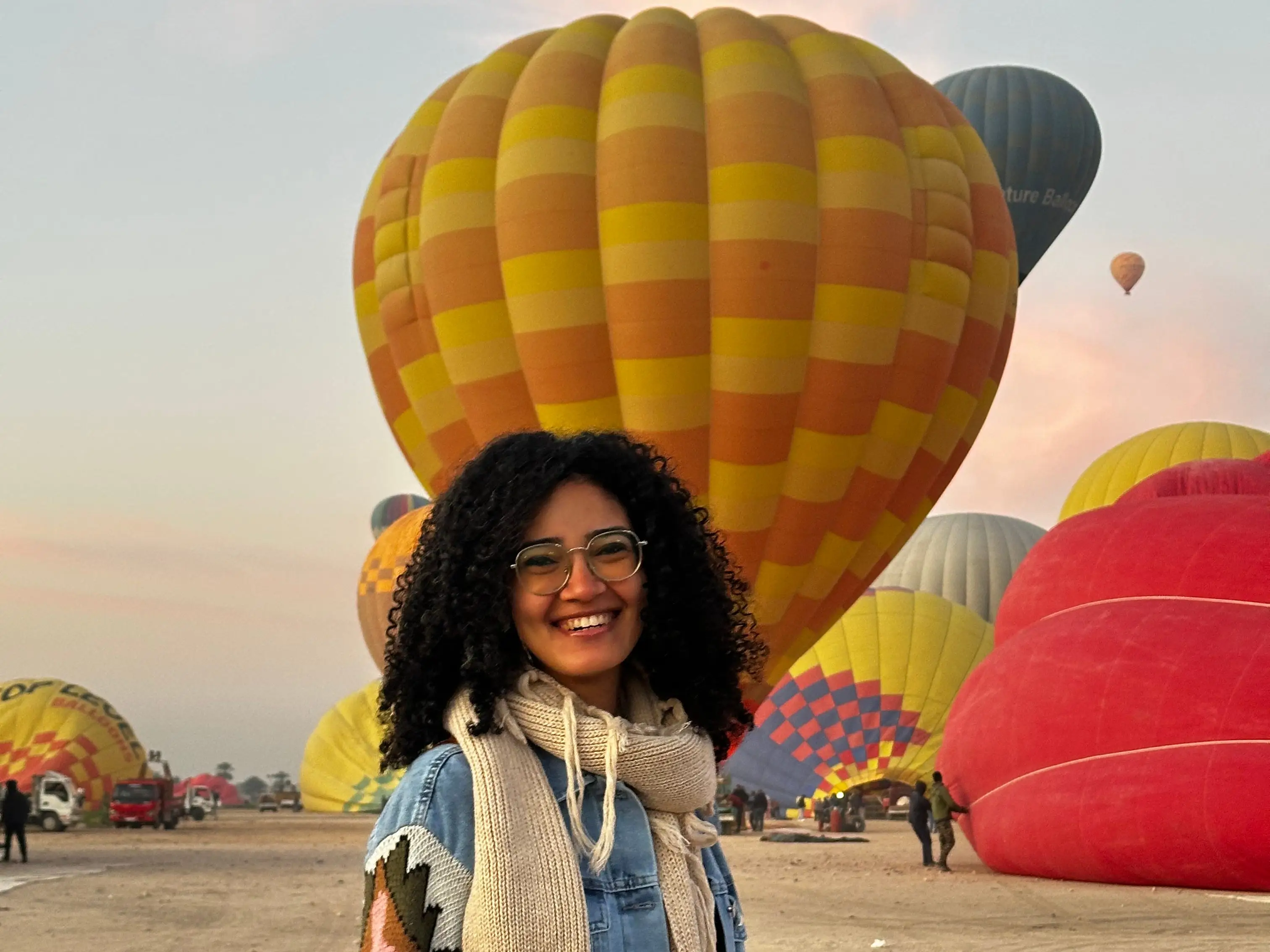 A woman standing in front of hot-air balloons in Luxor, Egypt.