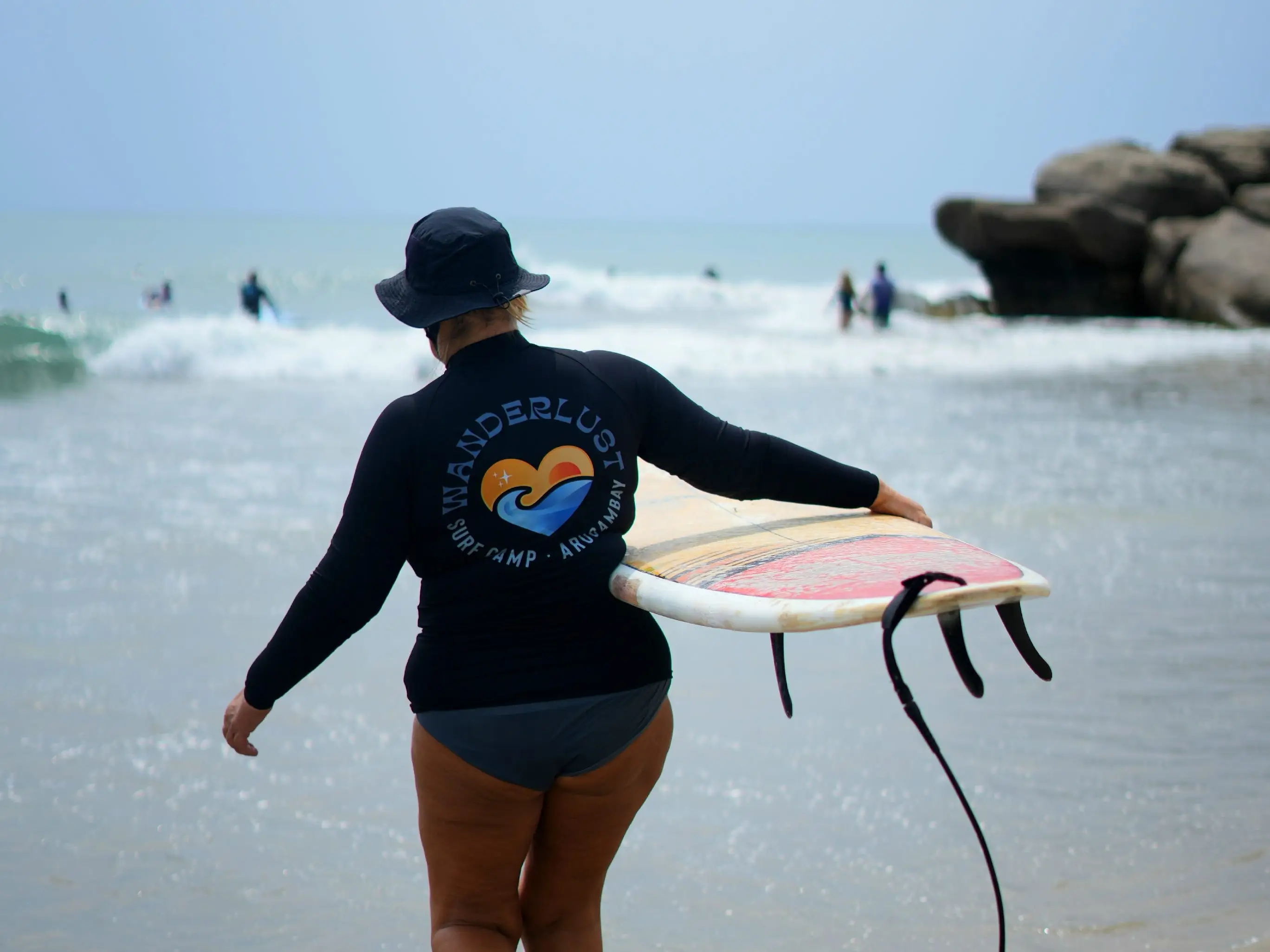 Back view of a woman holding her surf board.