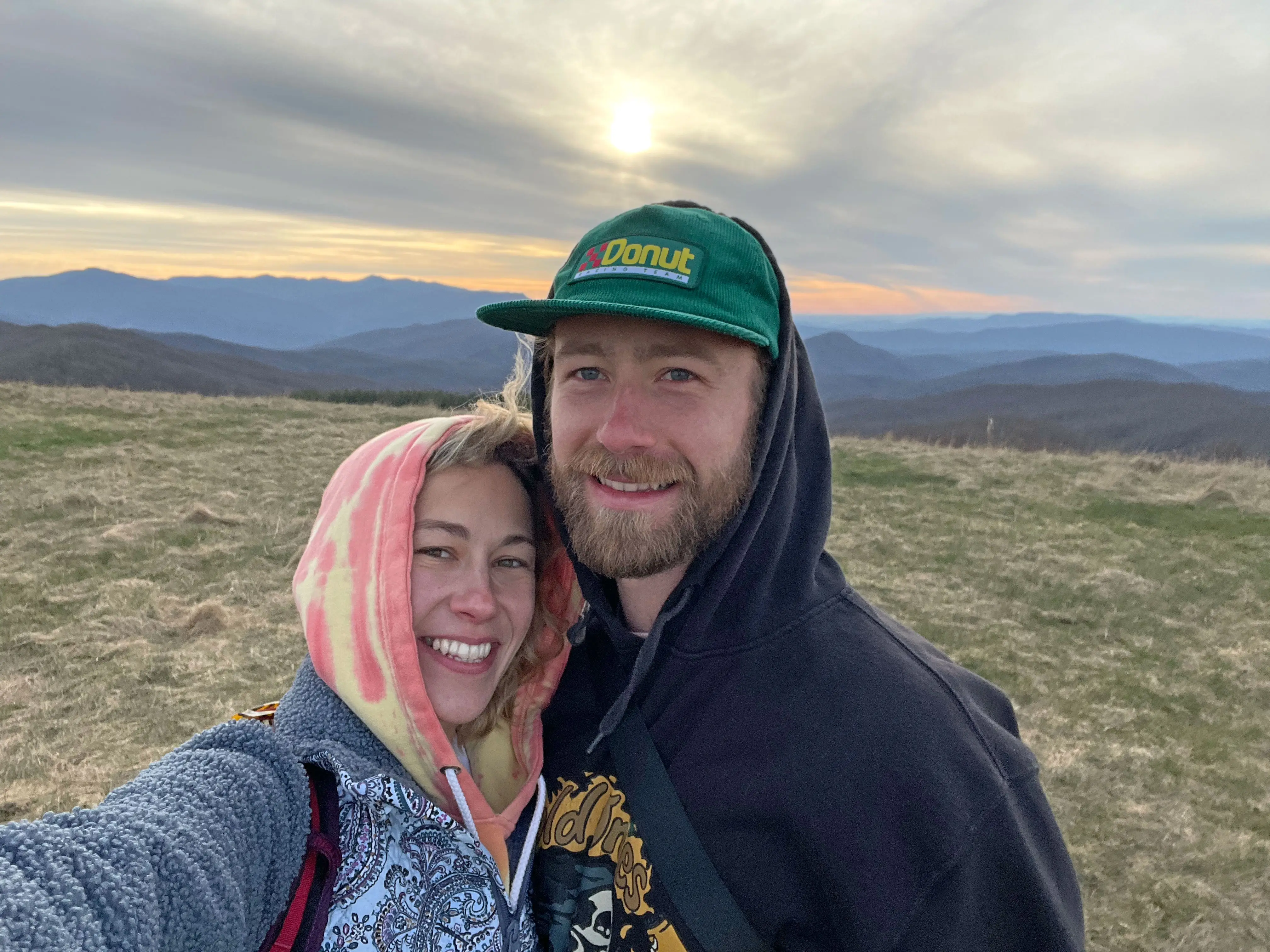 A man and women pose with mountains in the background.