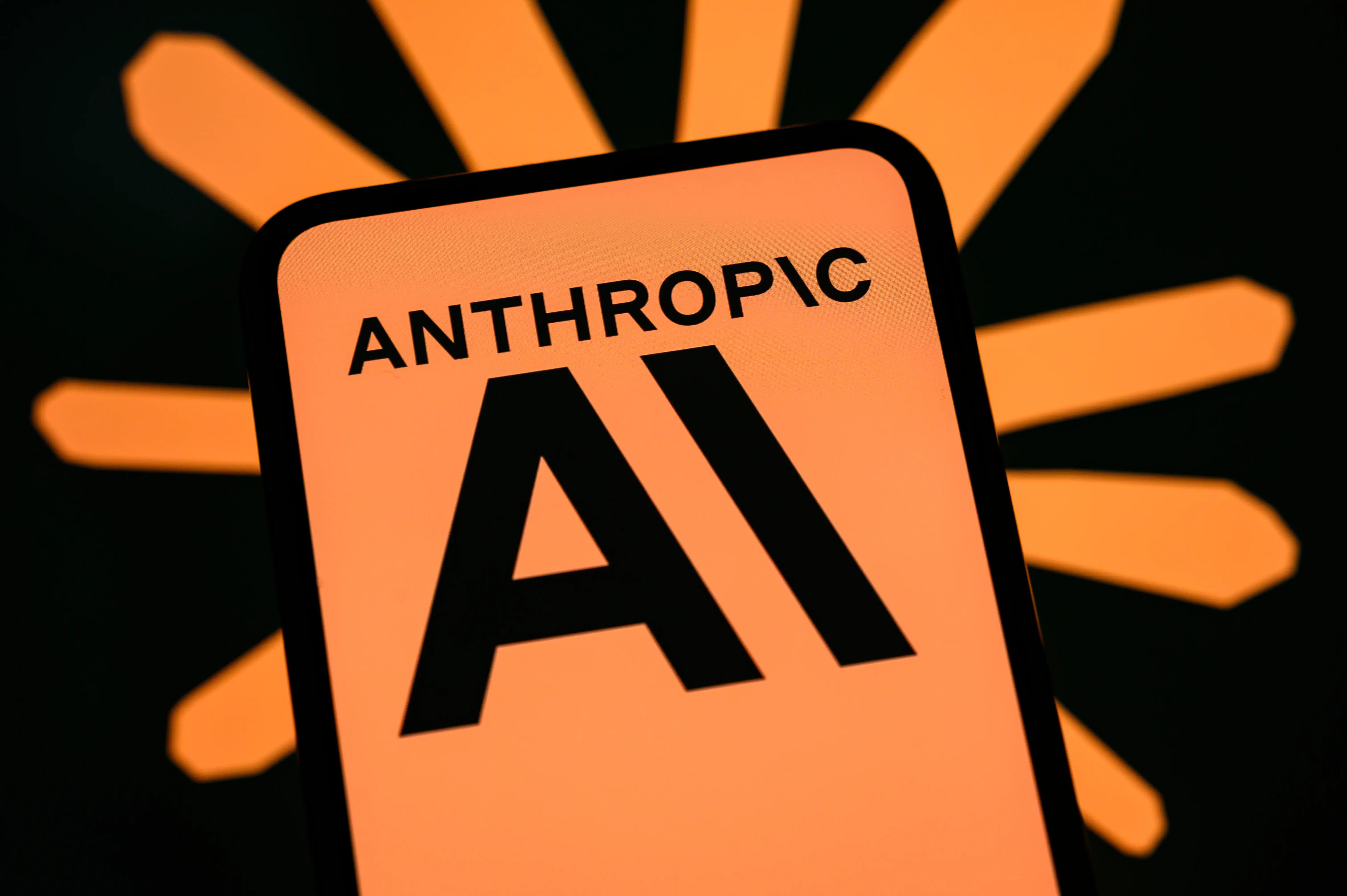 A phone with an orange Anthropic logo in front of a black background.