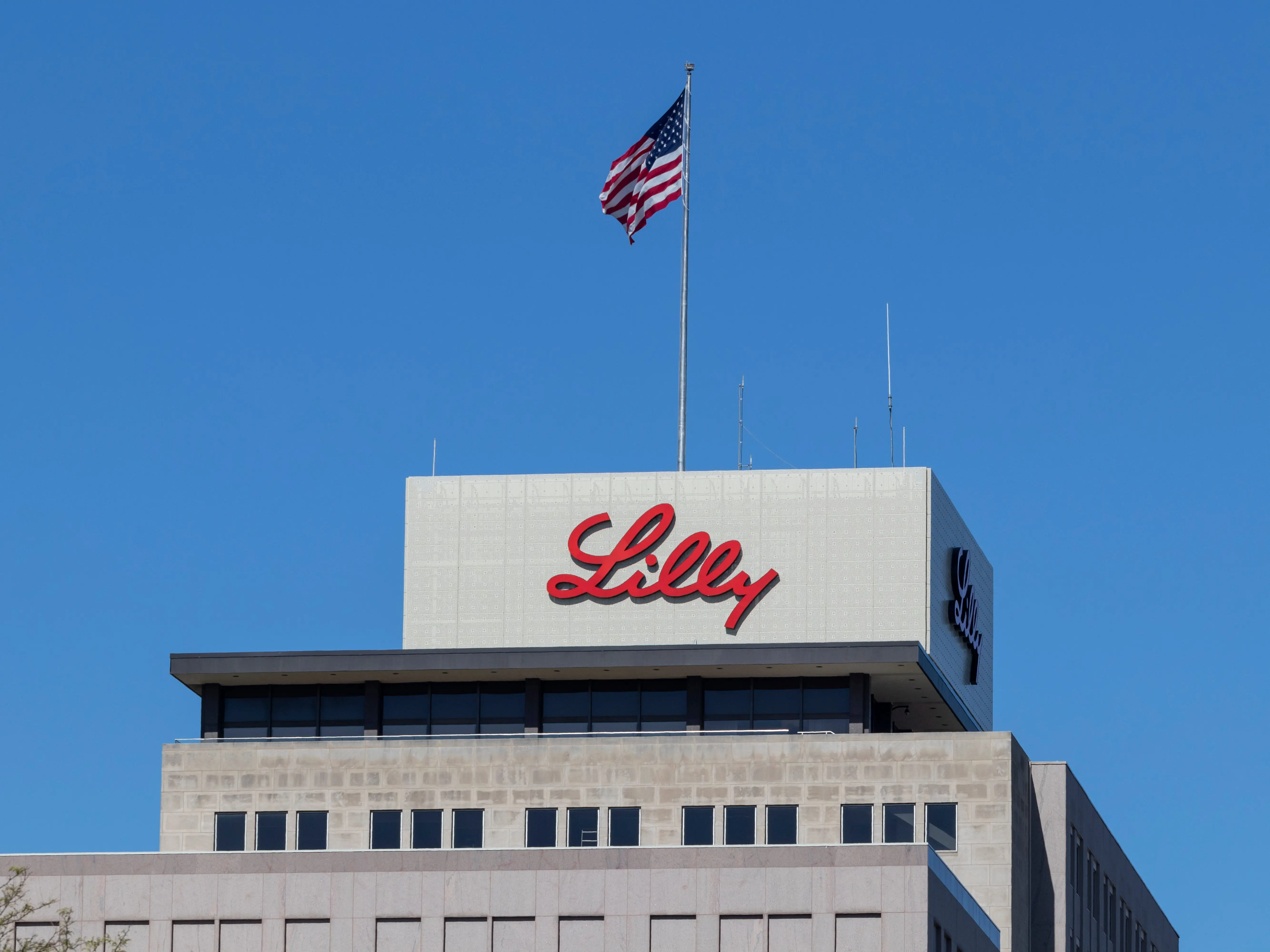 Eli Lilly logo on building under an American flag
