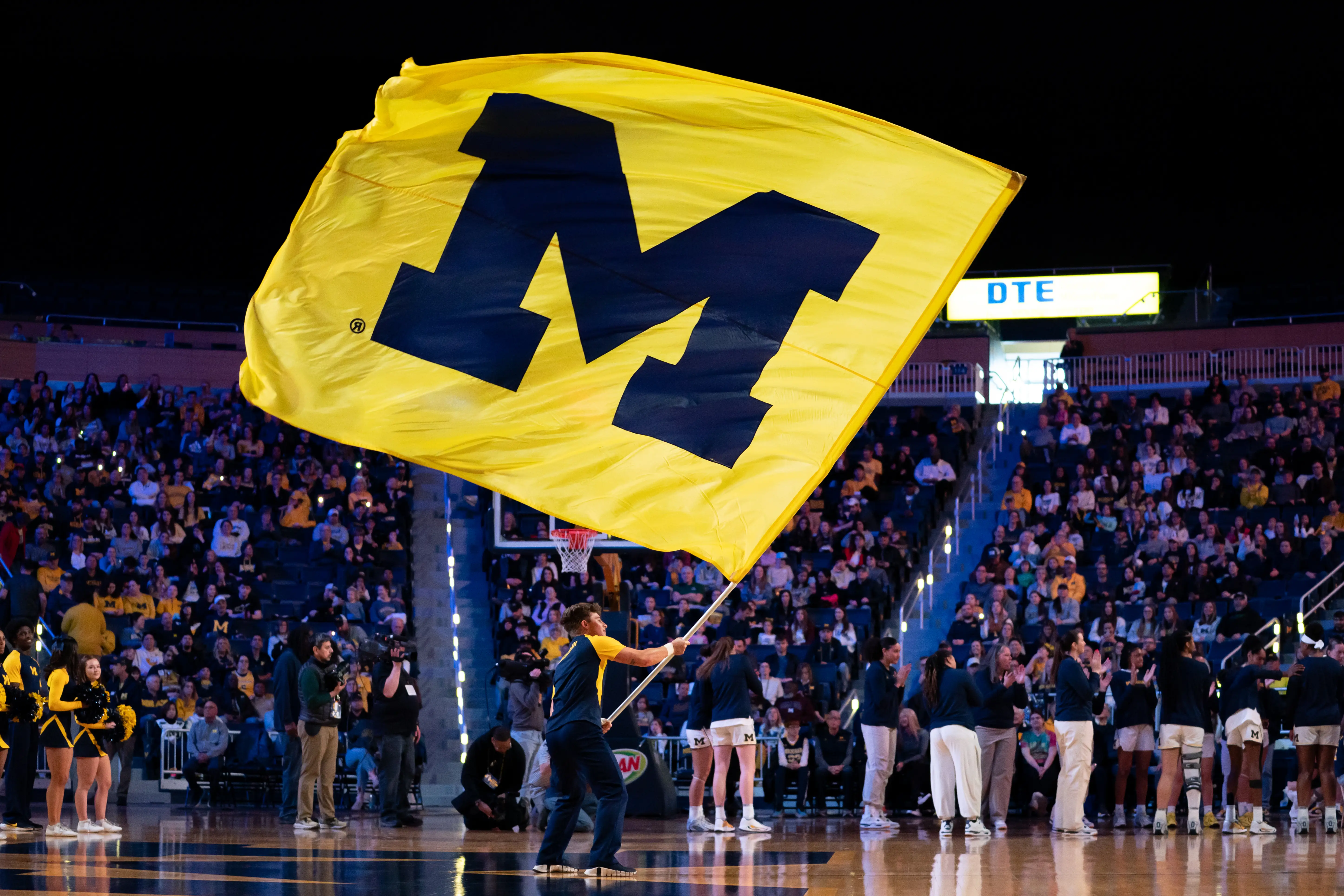 A University of Michigan flag is waved at an athletic event.