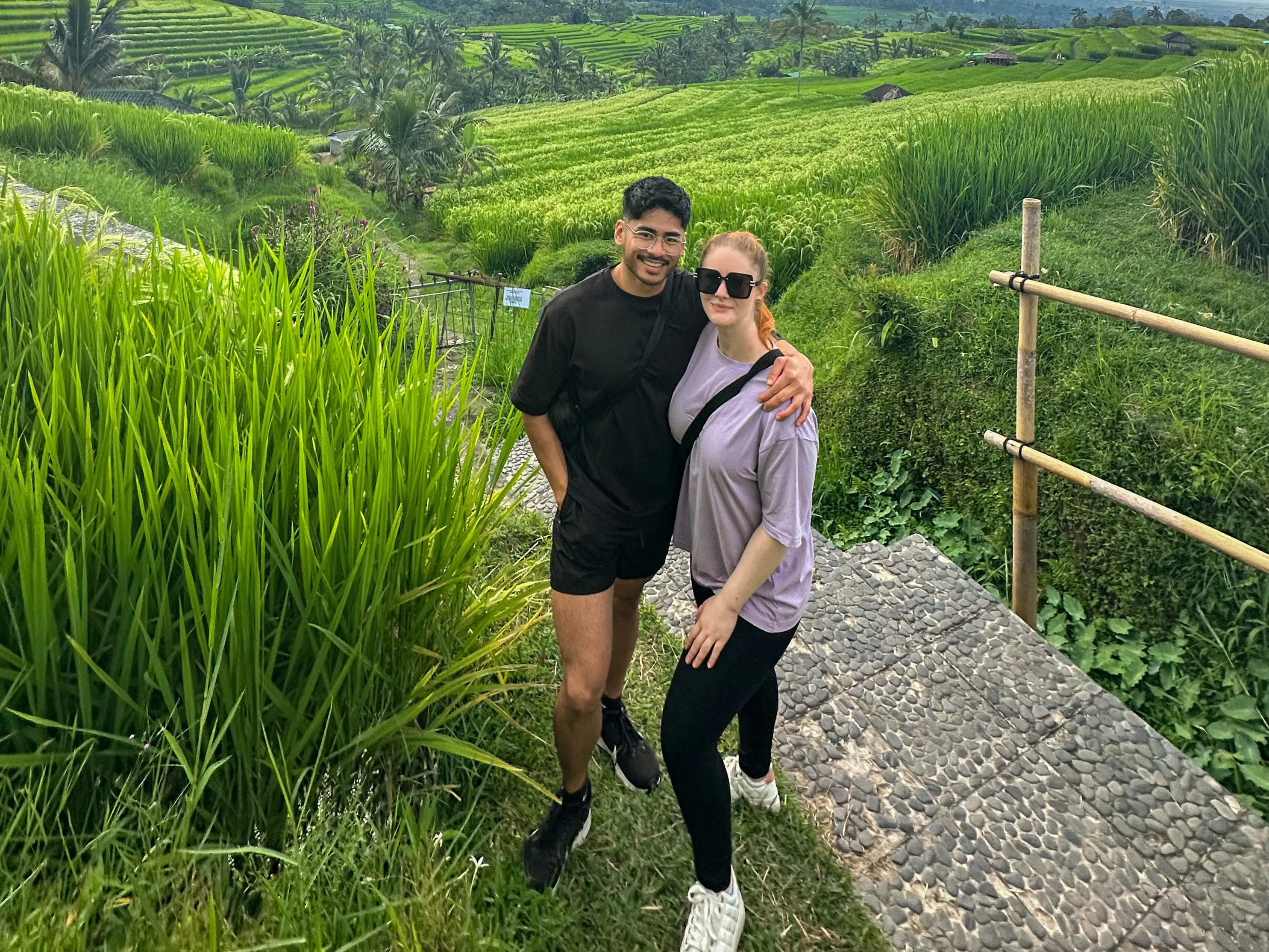 Man and woman posing in front of fields under overcast sky