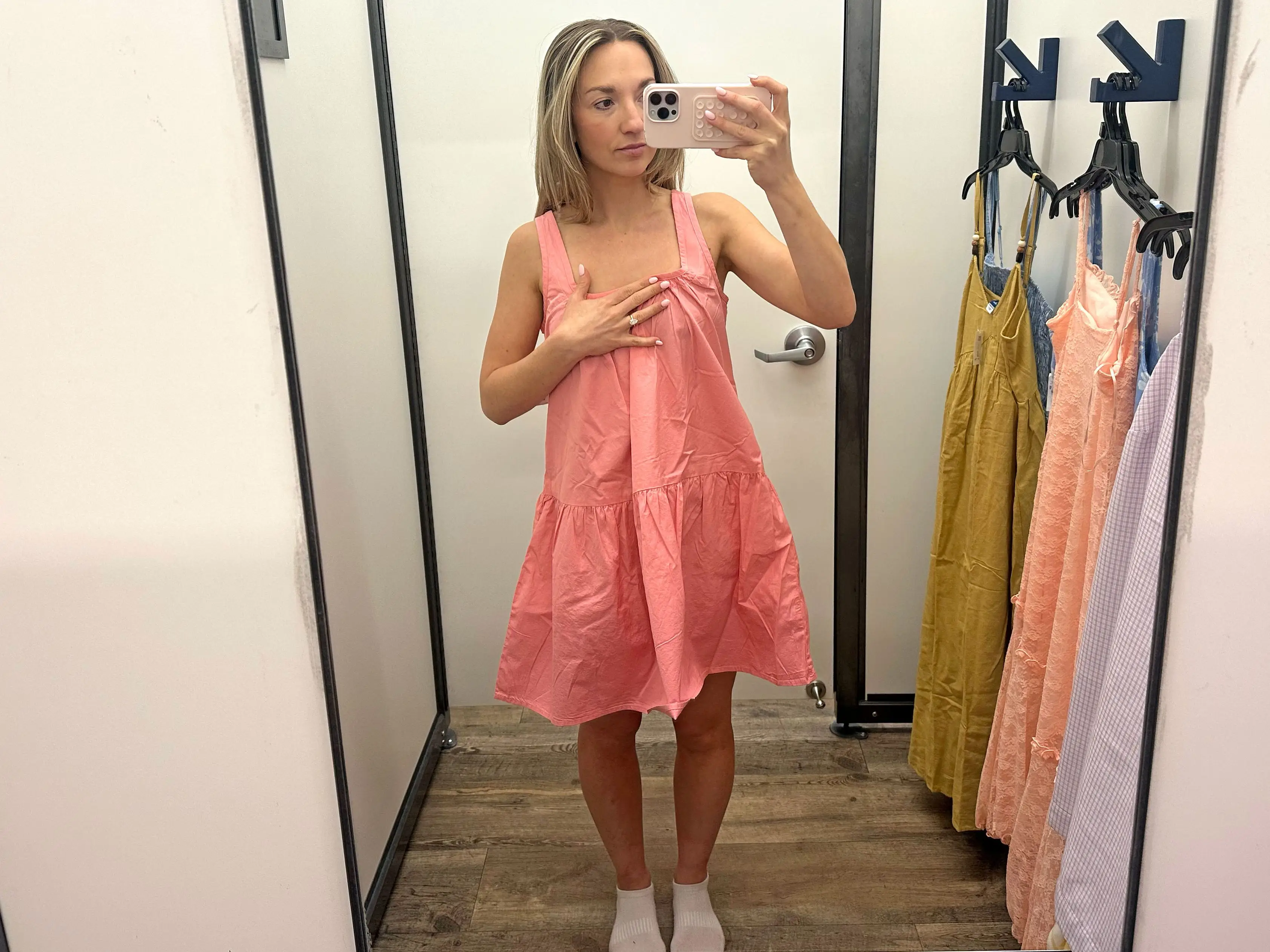 Chloe wearing a short pink dress and holding on to the top portion.