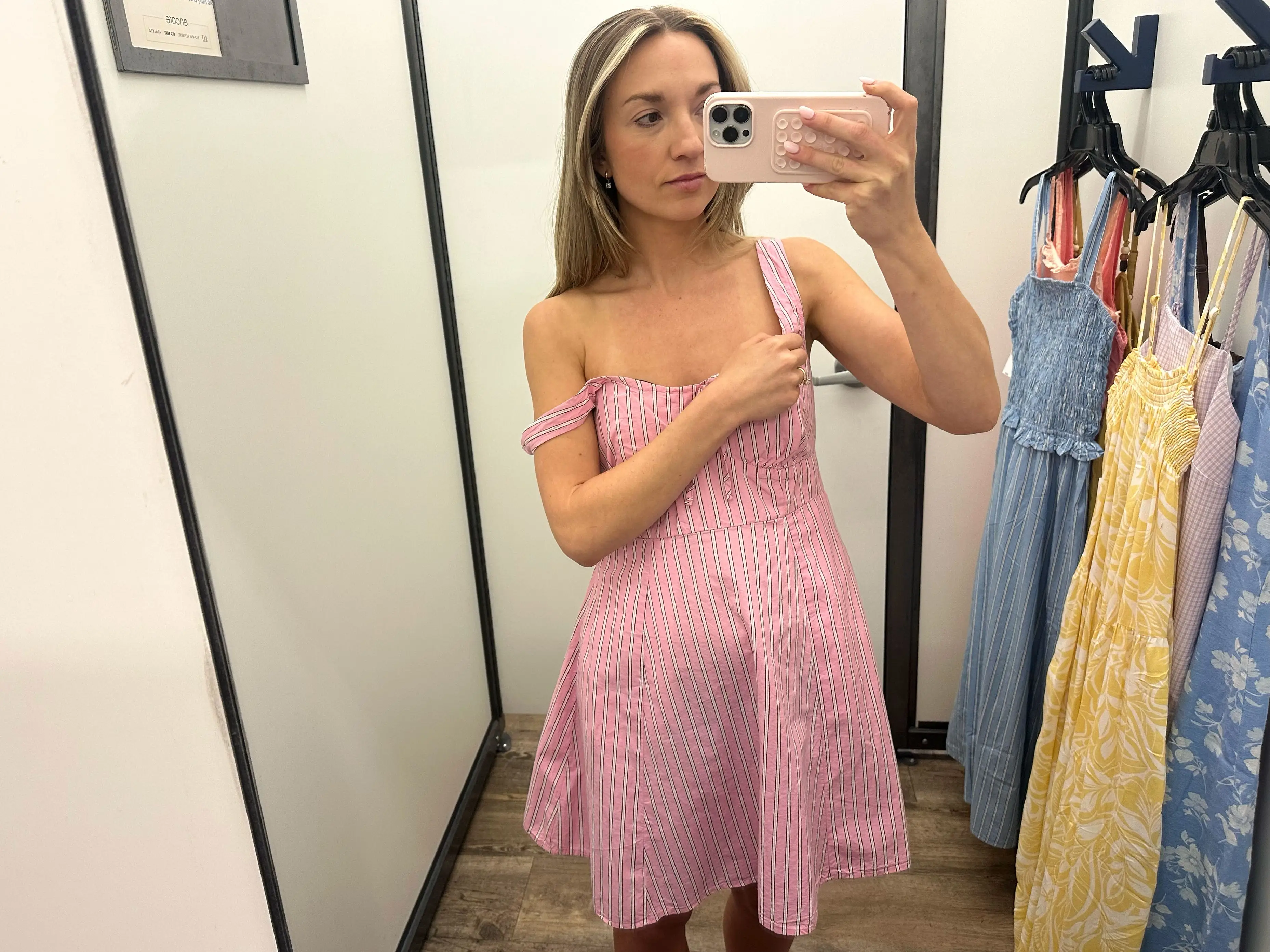 Chloe wearing a pink and white striped mini dress, with one of the straps hanging off her shoulder.