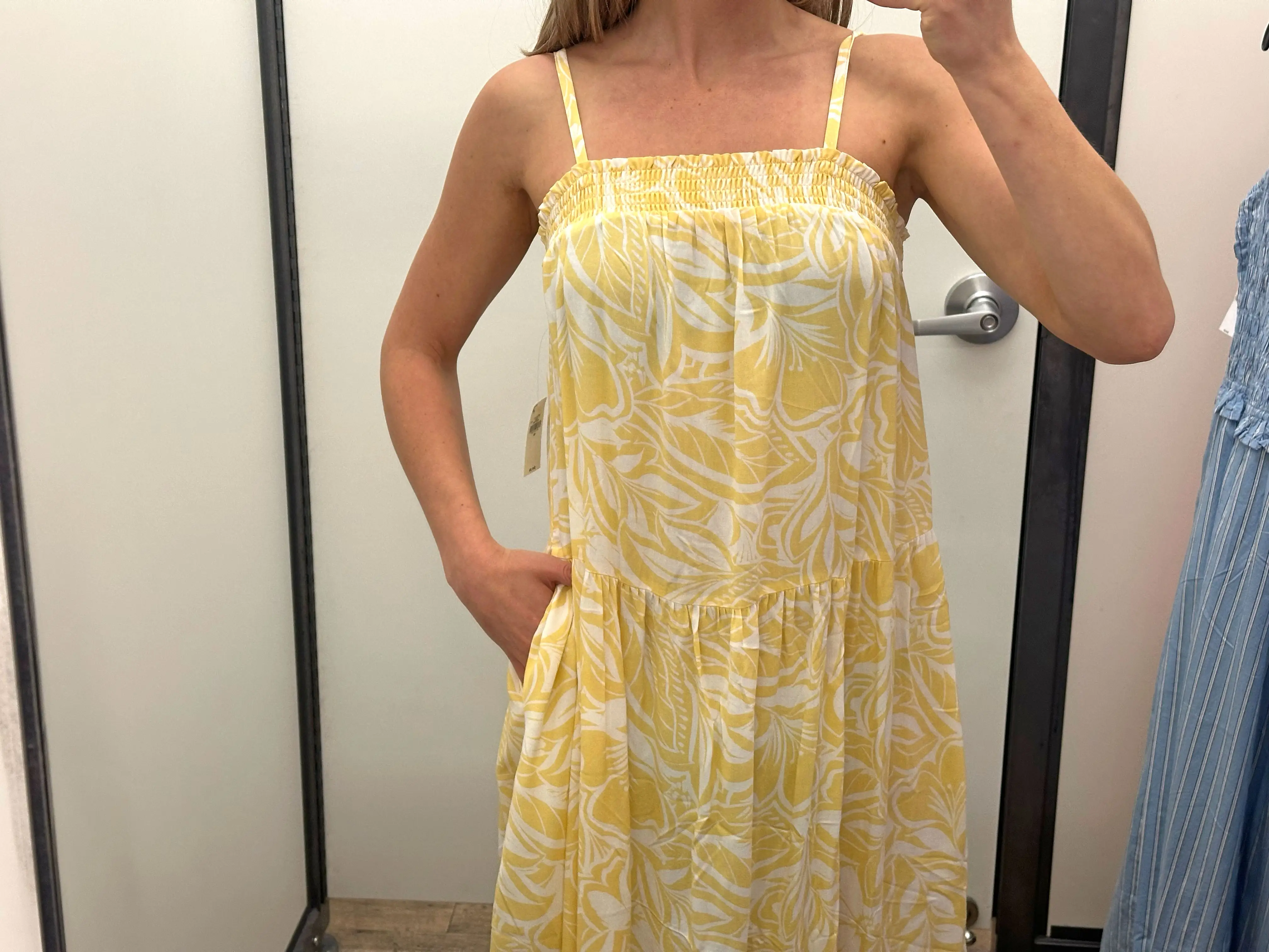 A close-up of Chloe wearing a yellow-and-white patterned maxi dress with pockets.