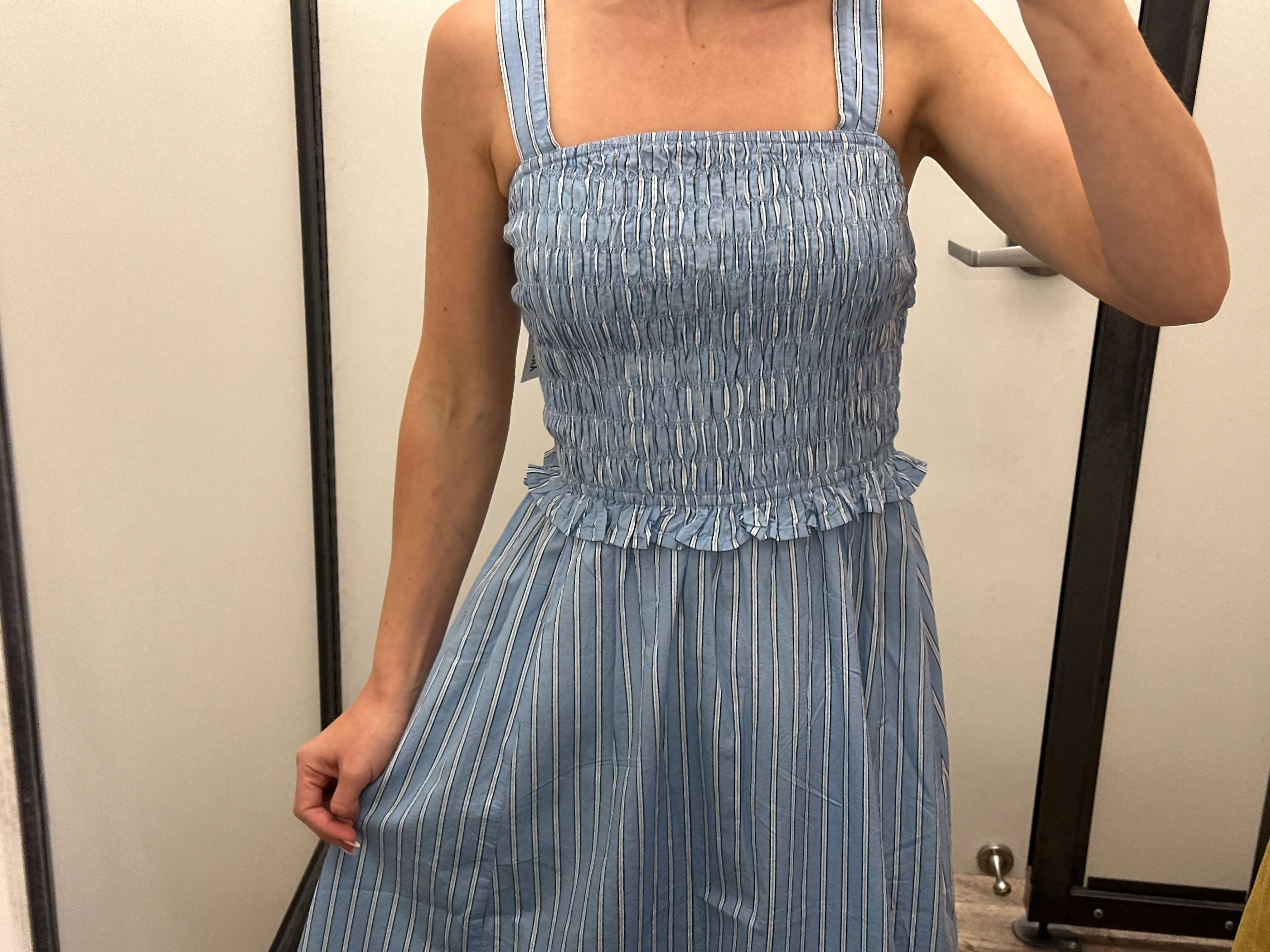 A close-up of Chloe wearing a blue-and-white striped midi dress.
