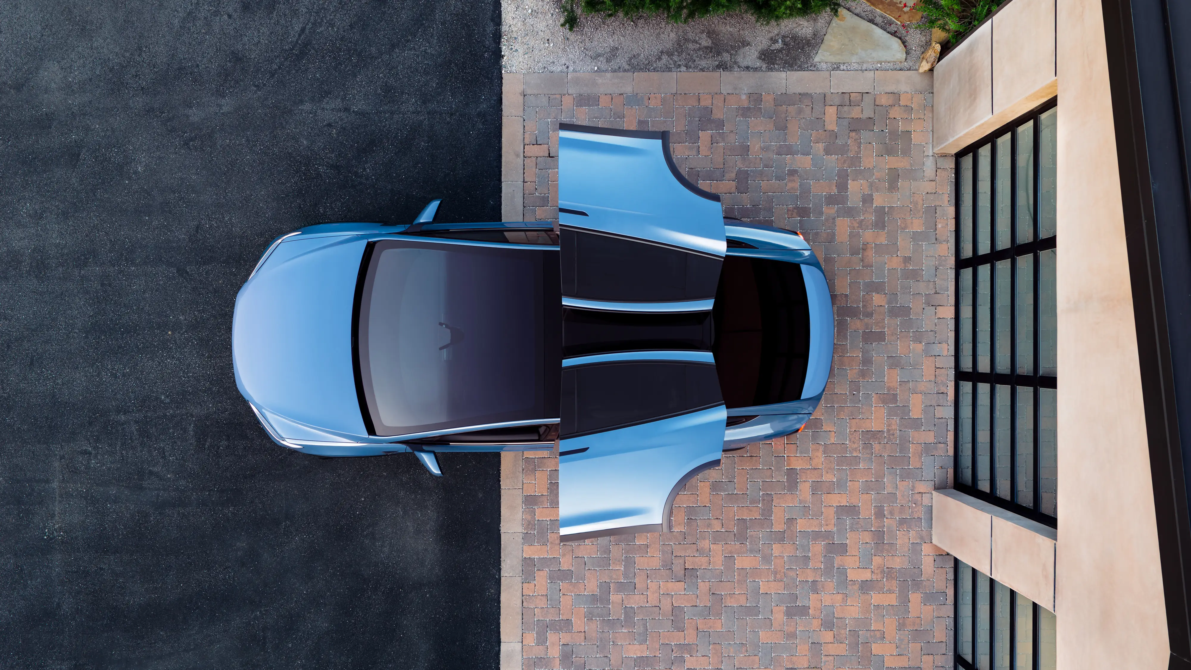 A blue Tesla Model X, pictured from above, with it's second-row, Falcon Wing doors opened.