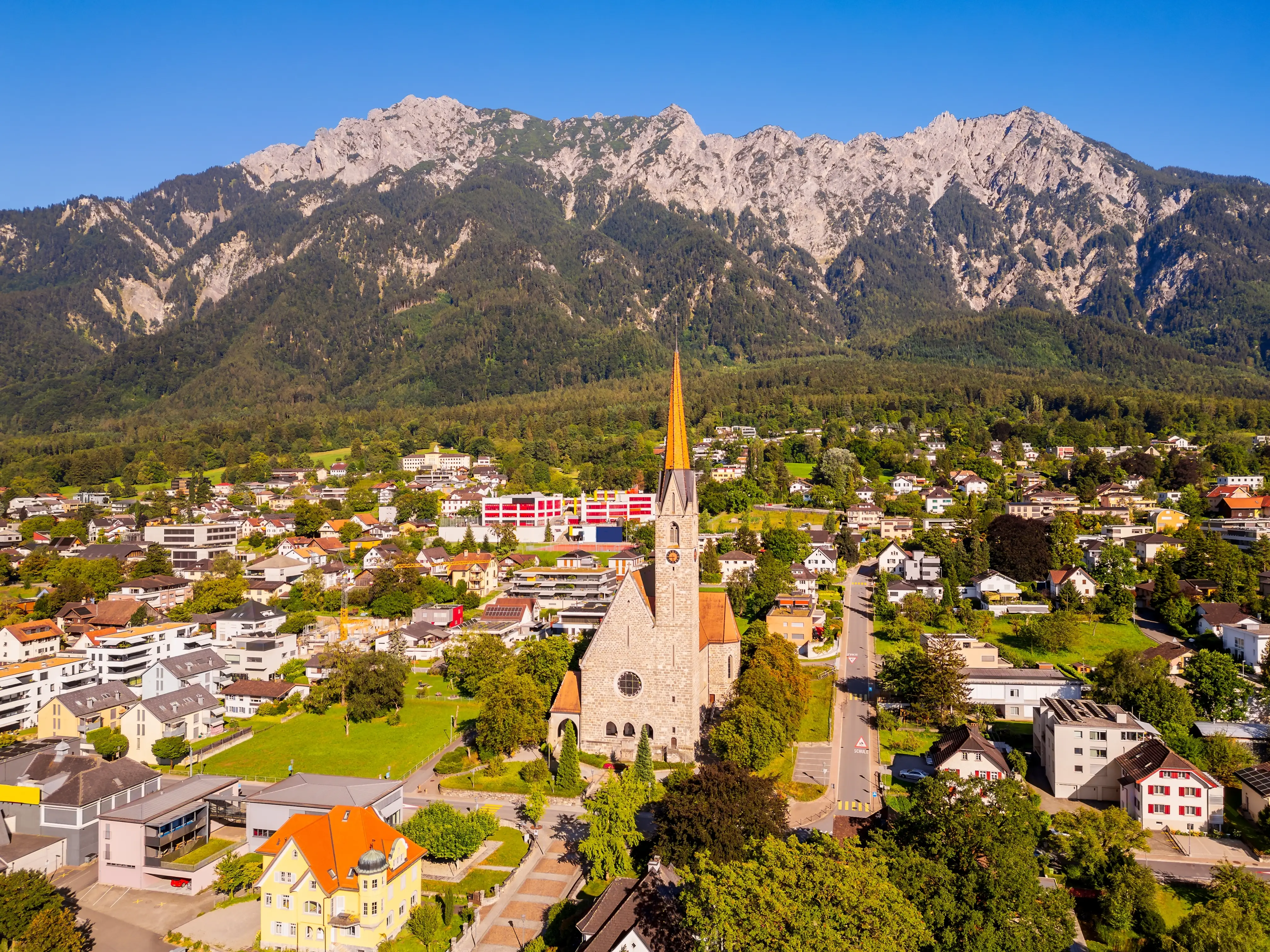 Church and houses in front of a mountain in Schaan, Liechtenstein.