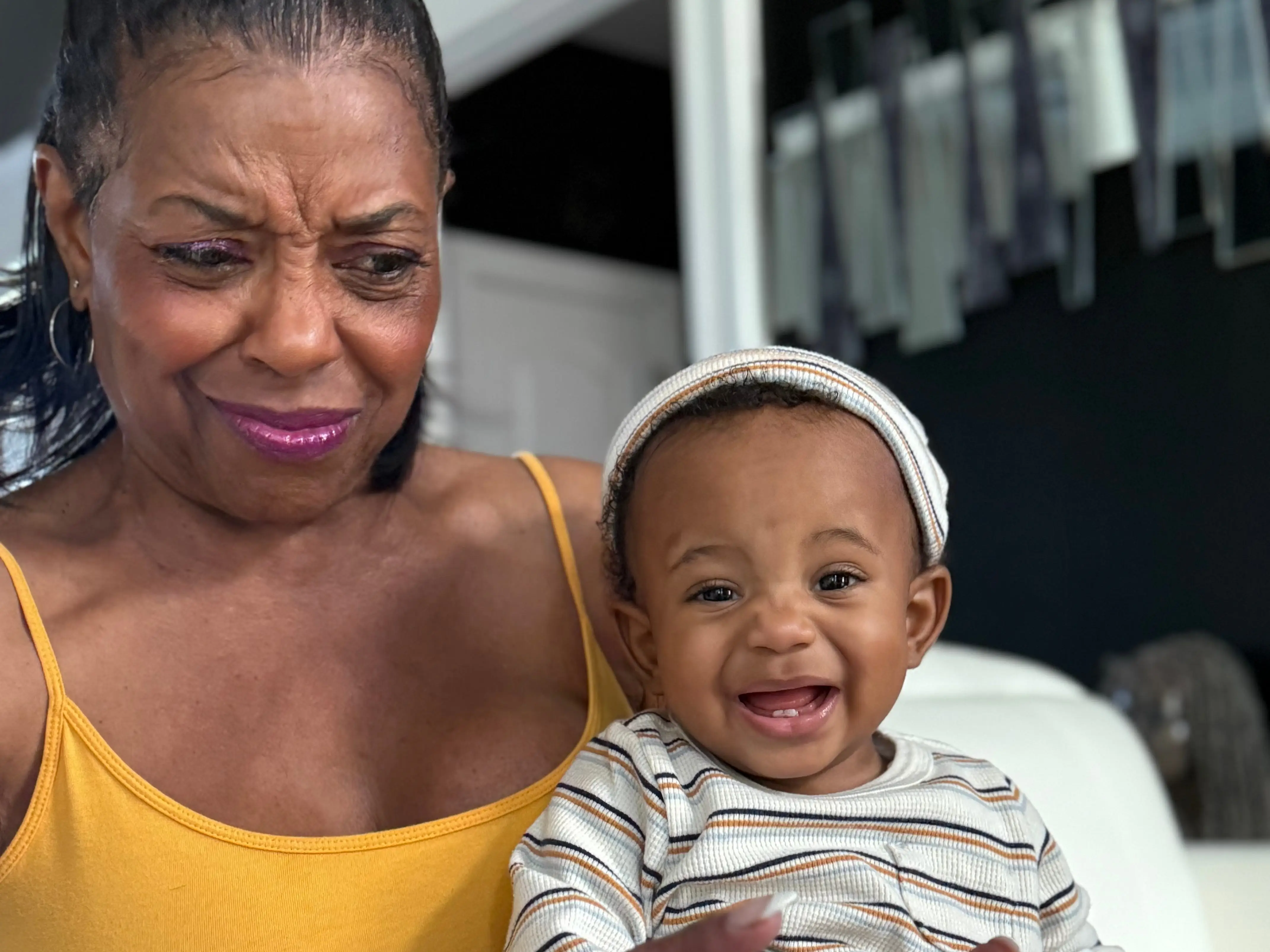 A woman in a yellow dress holding a baby boy.