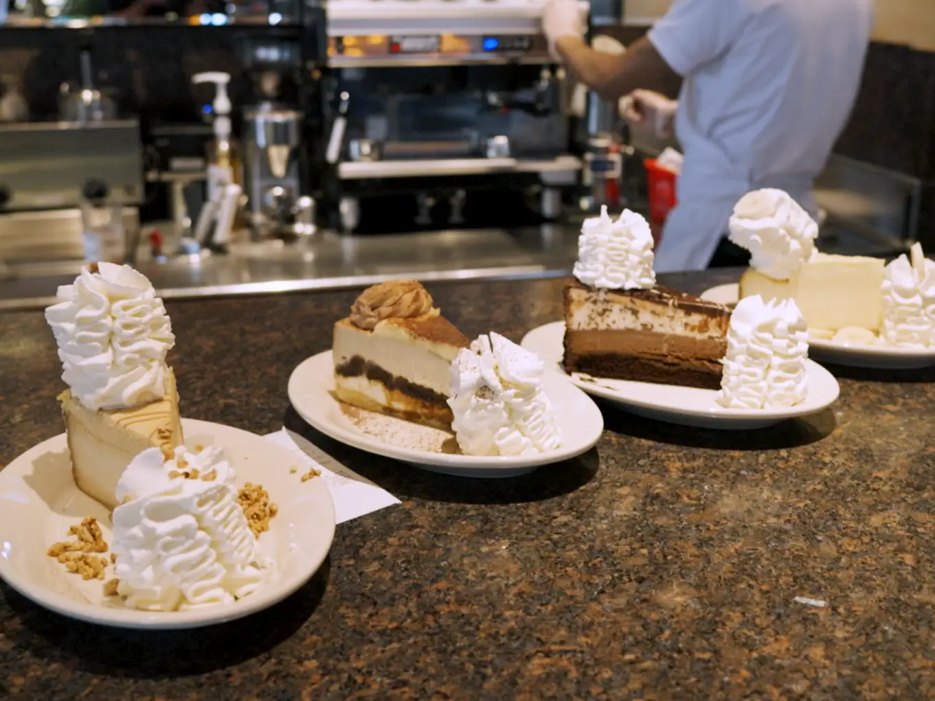 Four plates with four different cheesecakes from The Cheesecake Factory.