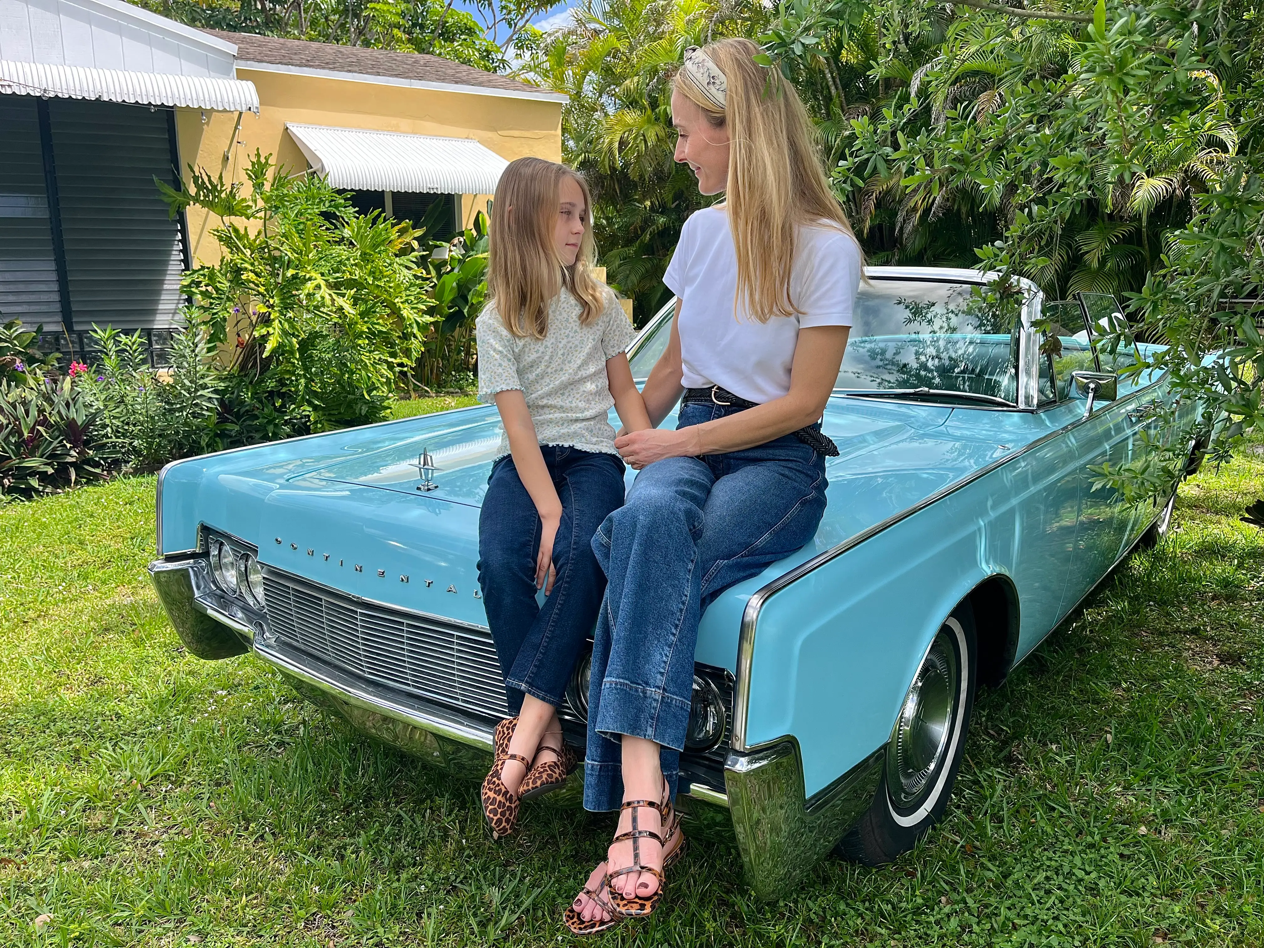 the author and her daughter sitting on the hood of a baby blue classic car