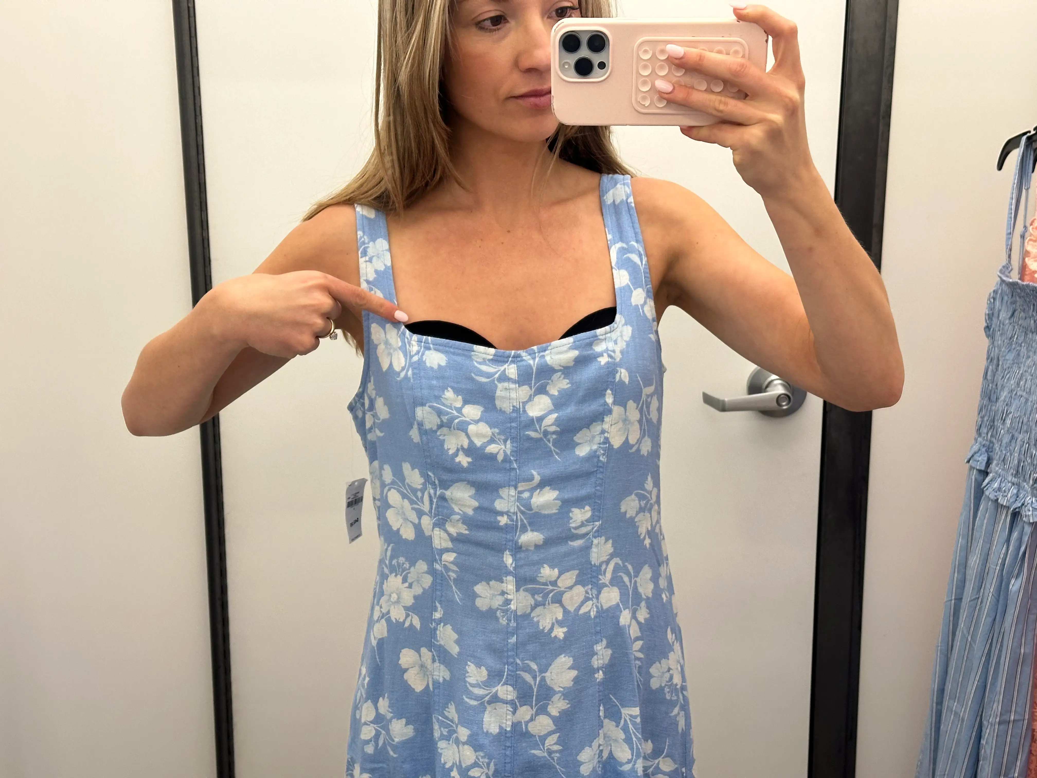 Chloe points to her bra sticking out of a blue floral-patterned dress.