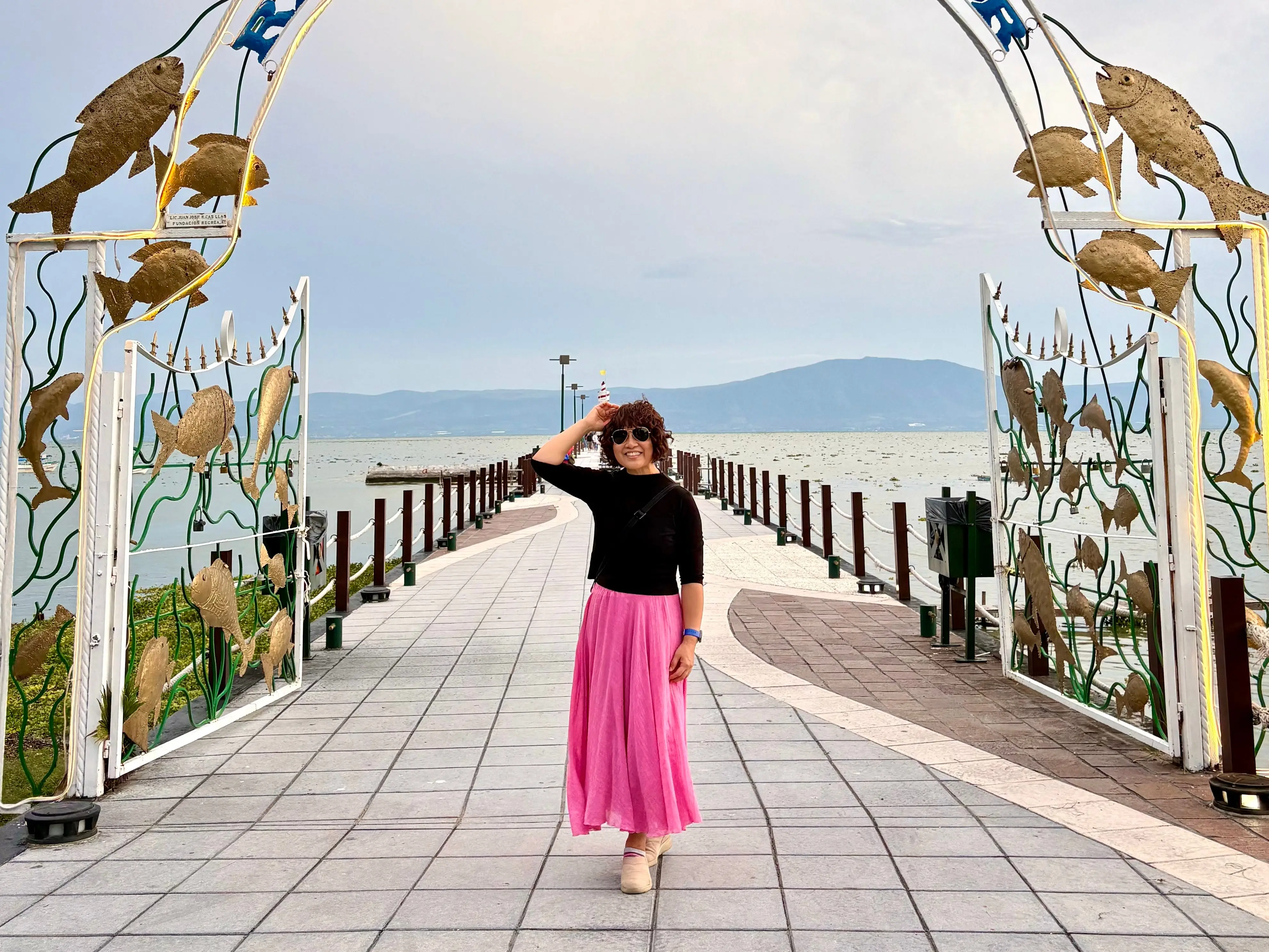 Woman posing below arch on pier