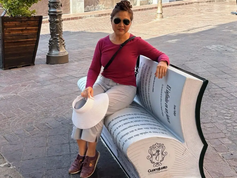 Woman sitting on book-shaped bench in Guanajuato Mexico
