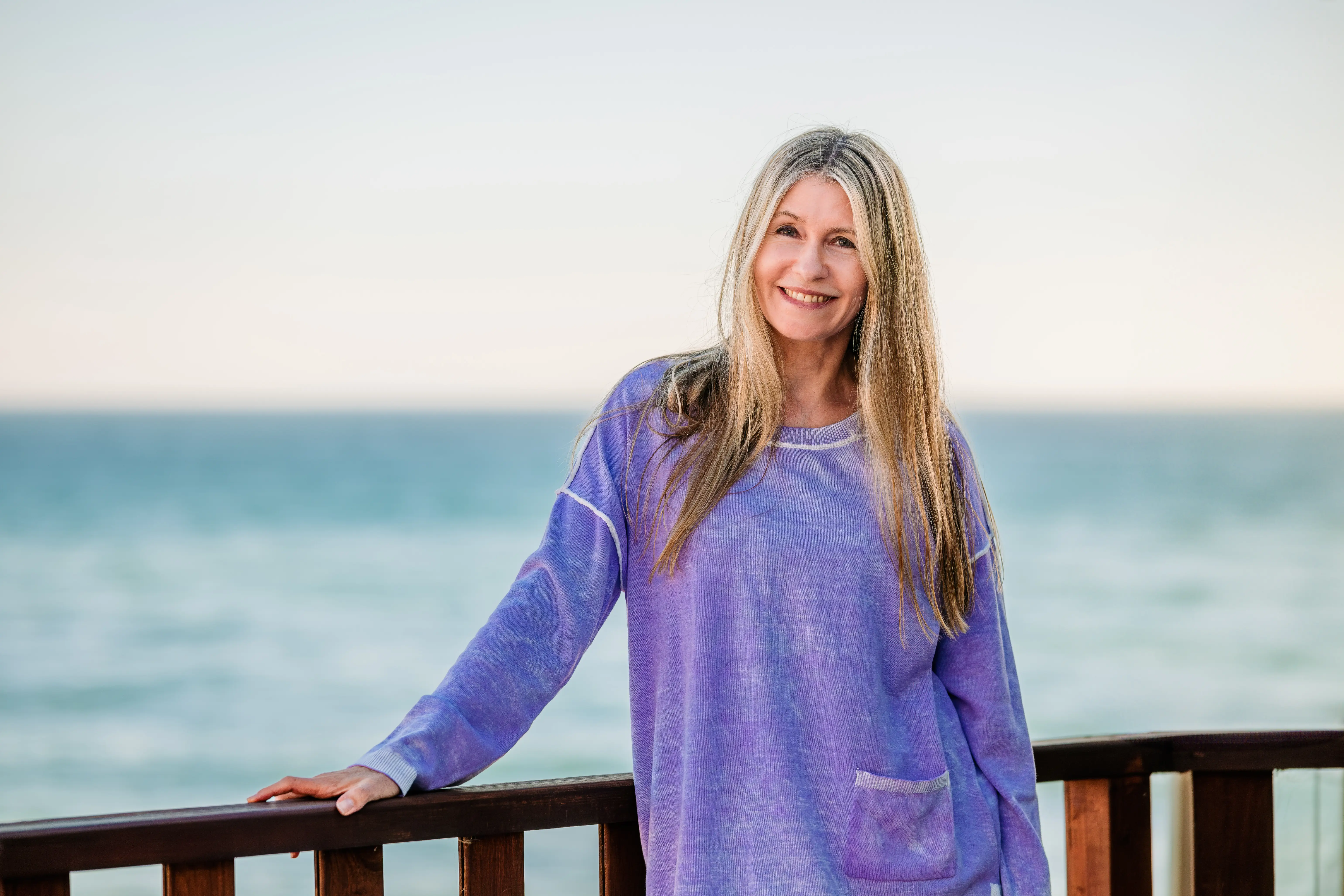 A woman stands in front of the ocean.