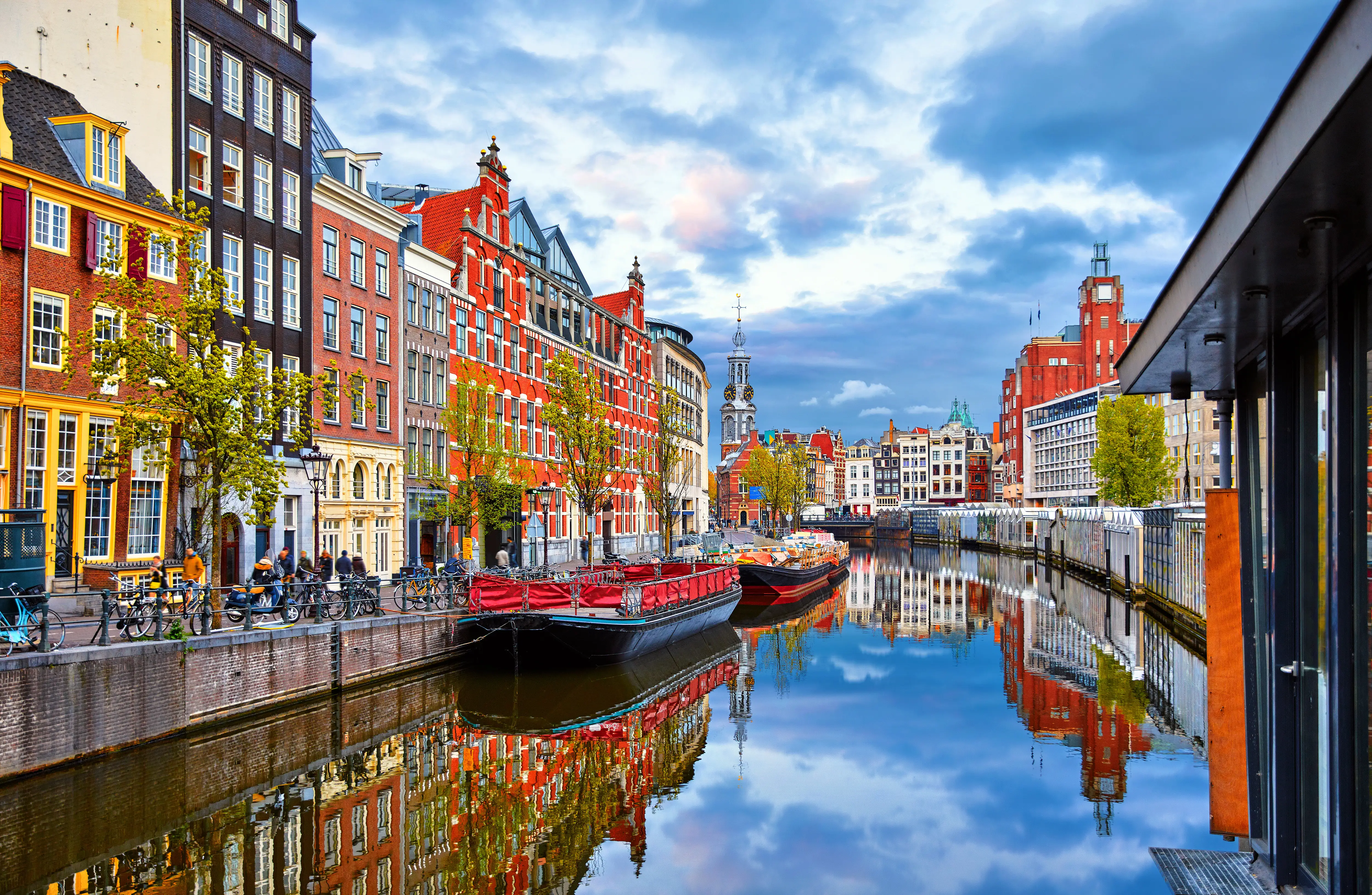 A channel in Amsterdam with colorful boats and homes.