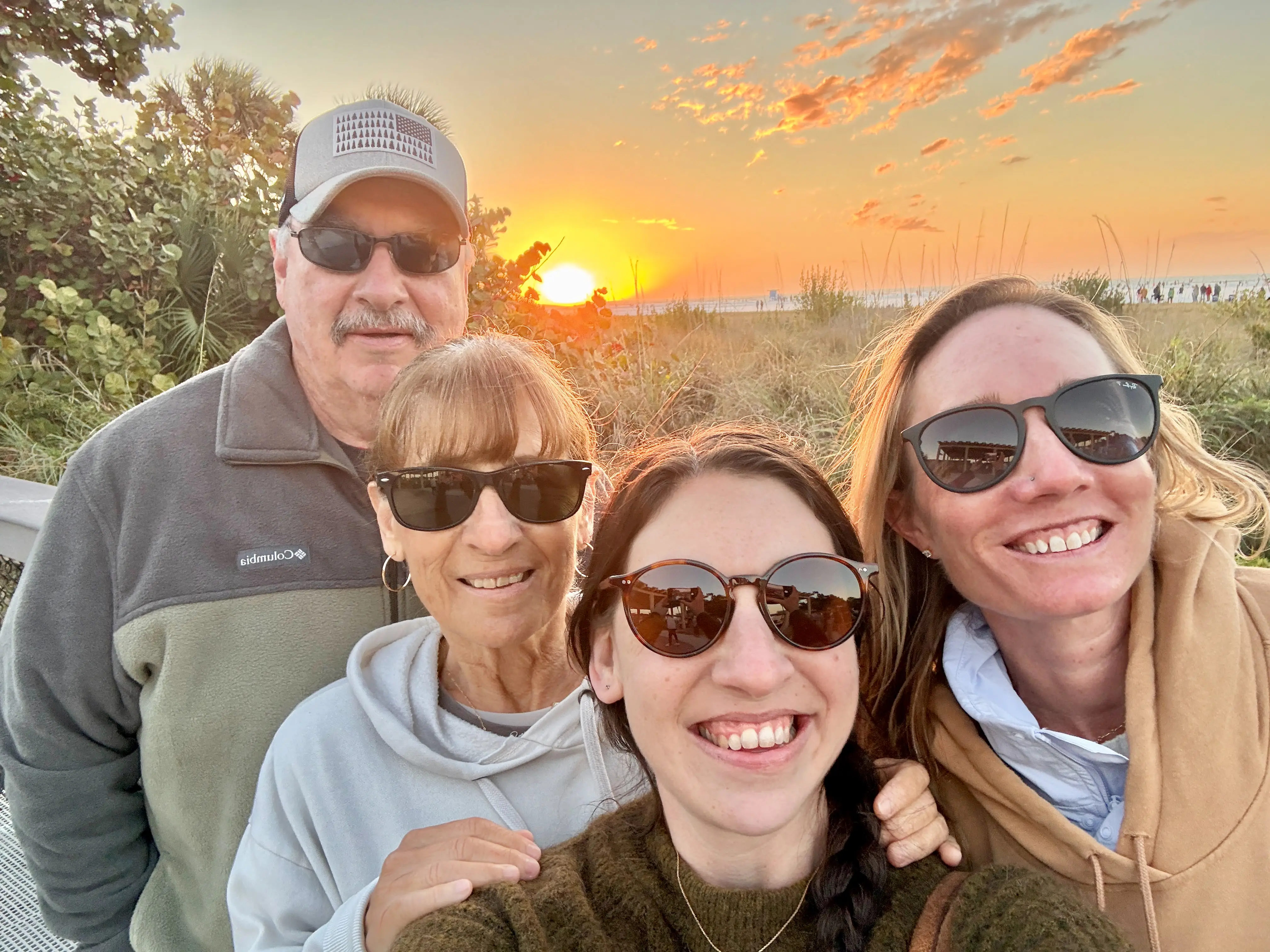 Group of four people in sunglasses smiling on beach