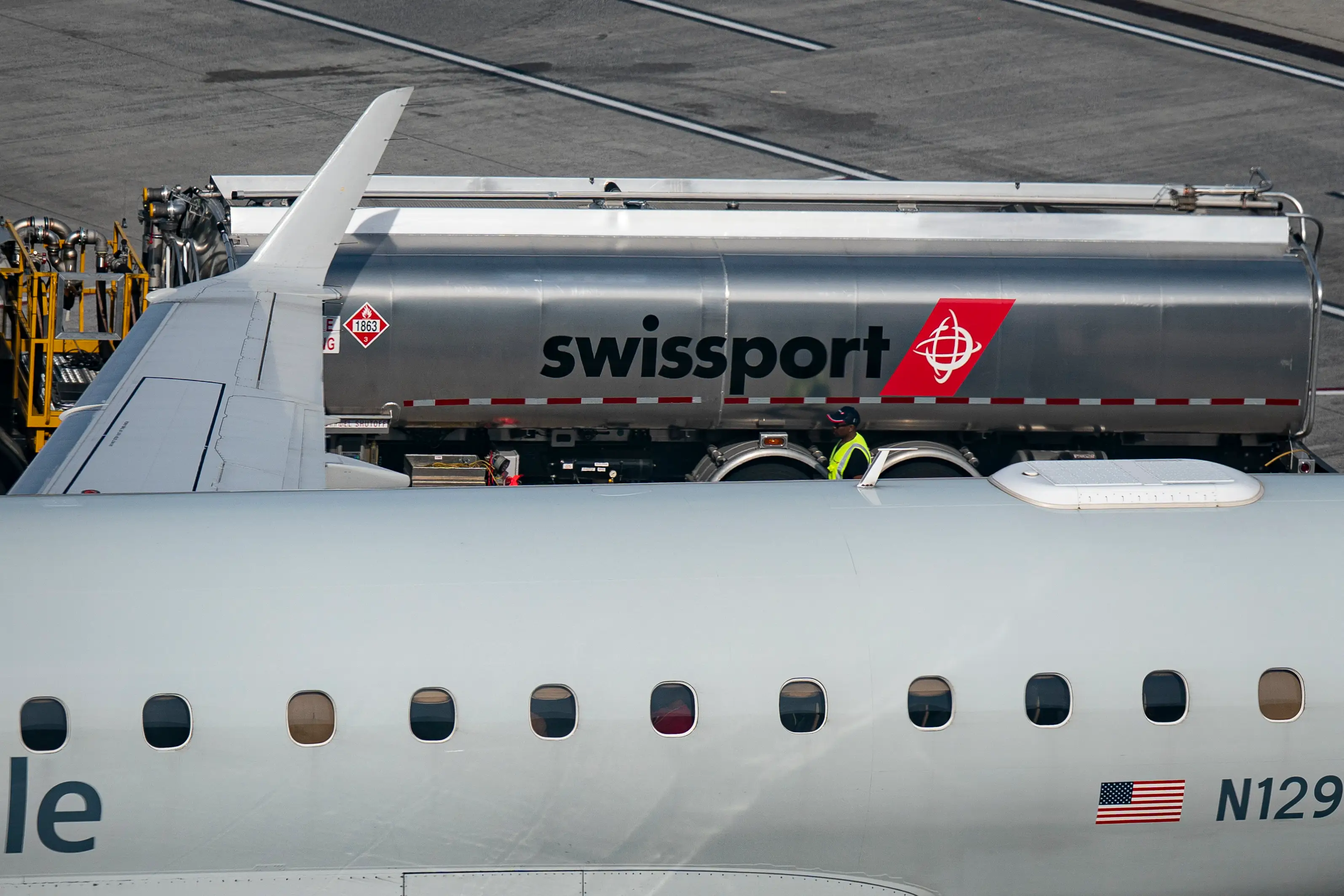 A swissport fuel truck fuels an American plane in NYC.