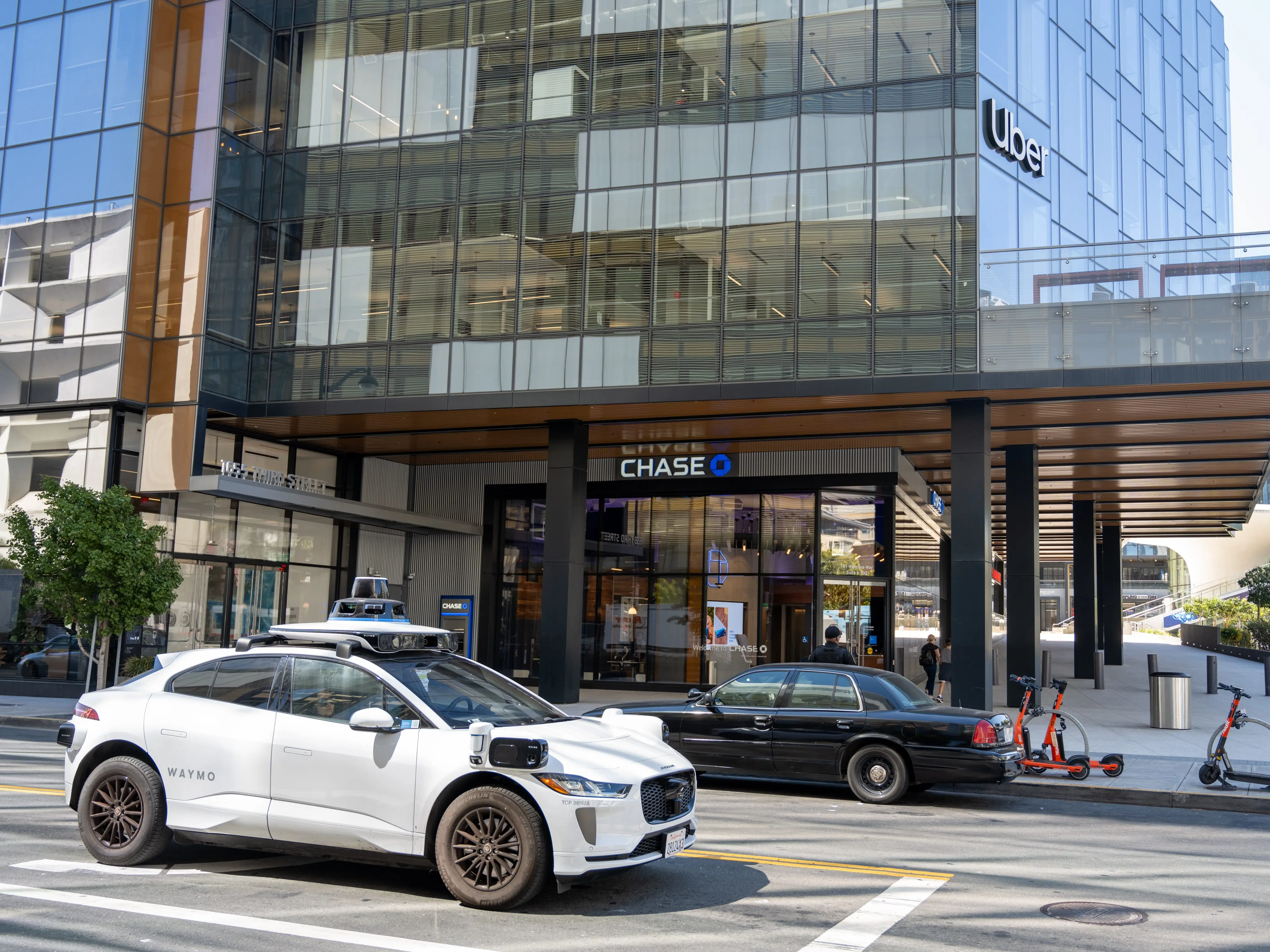 A Waymo robotaxi drives by Uber HQ in San Francisco