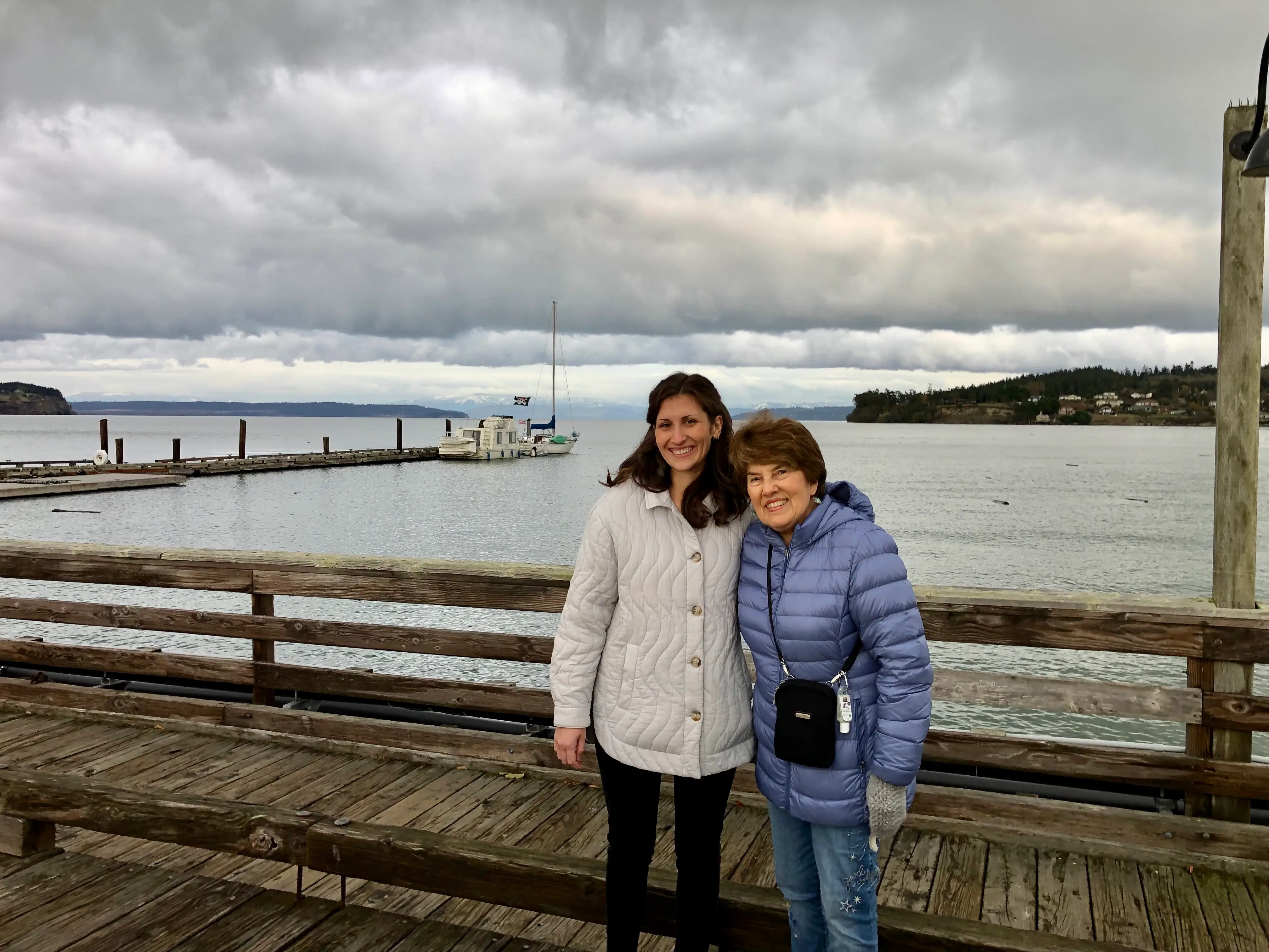 Author Cheyenne Elwell posing with woman on Whidbey Island in front of water, both wearing jackets