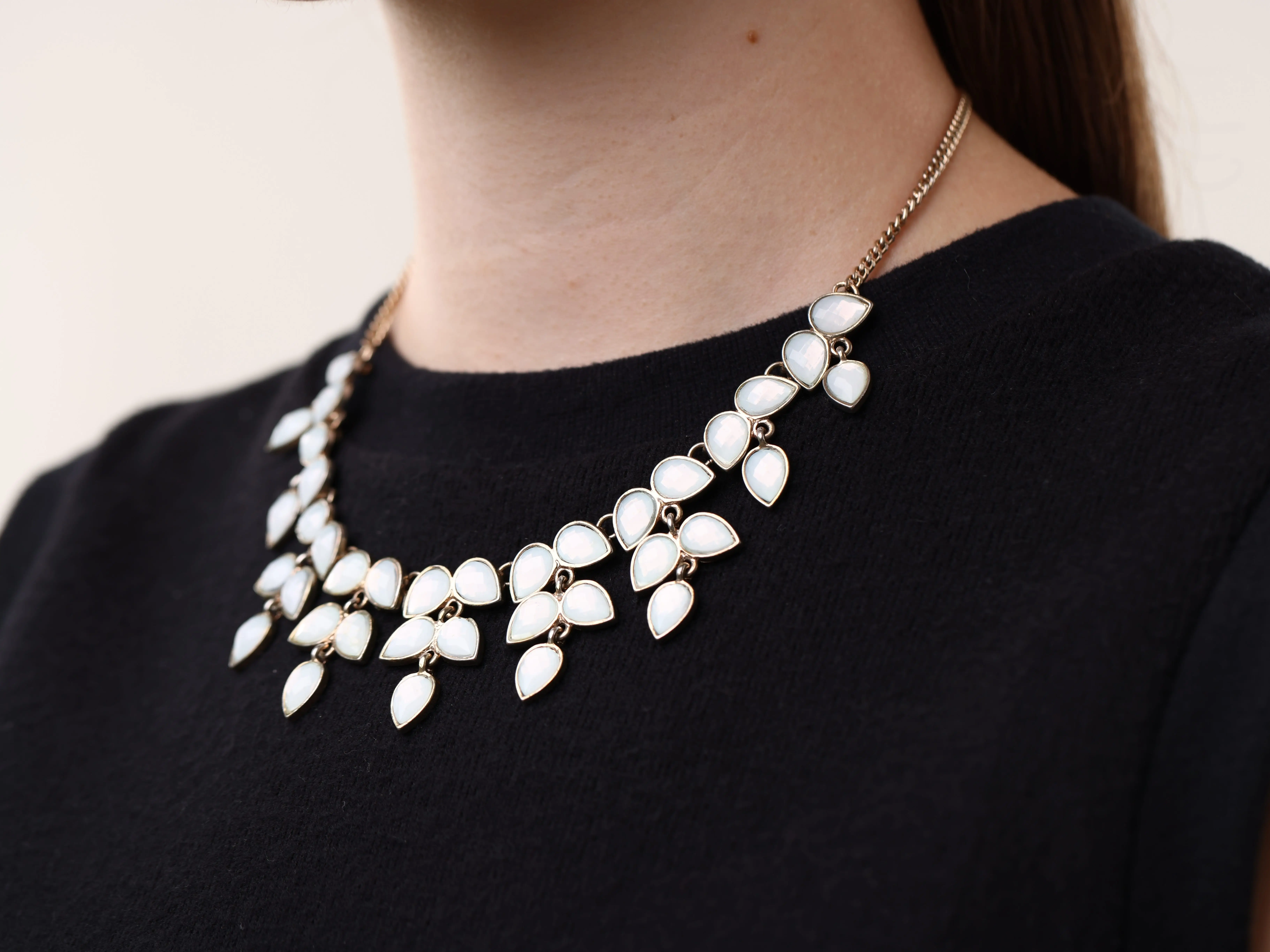 A white chunky statement necklace worn with a black T-shirt.