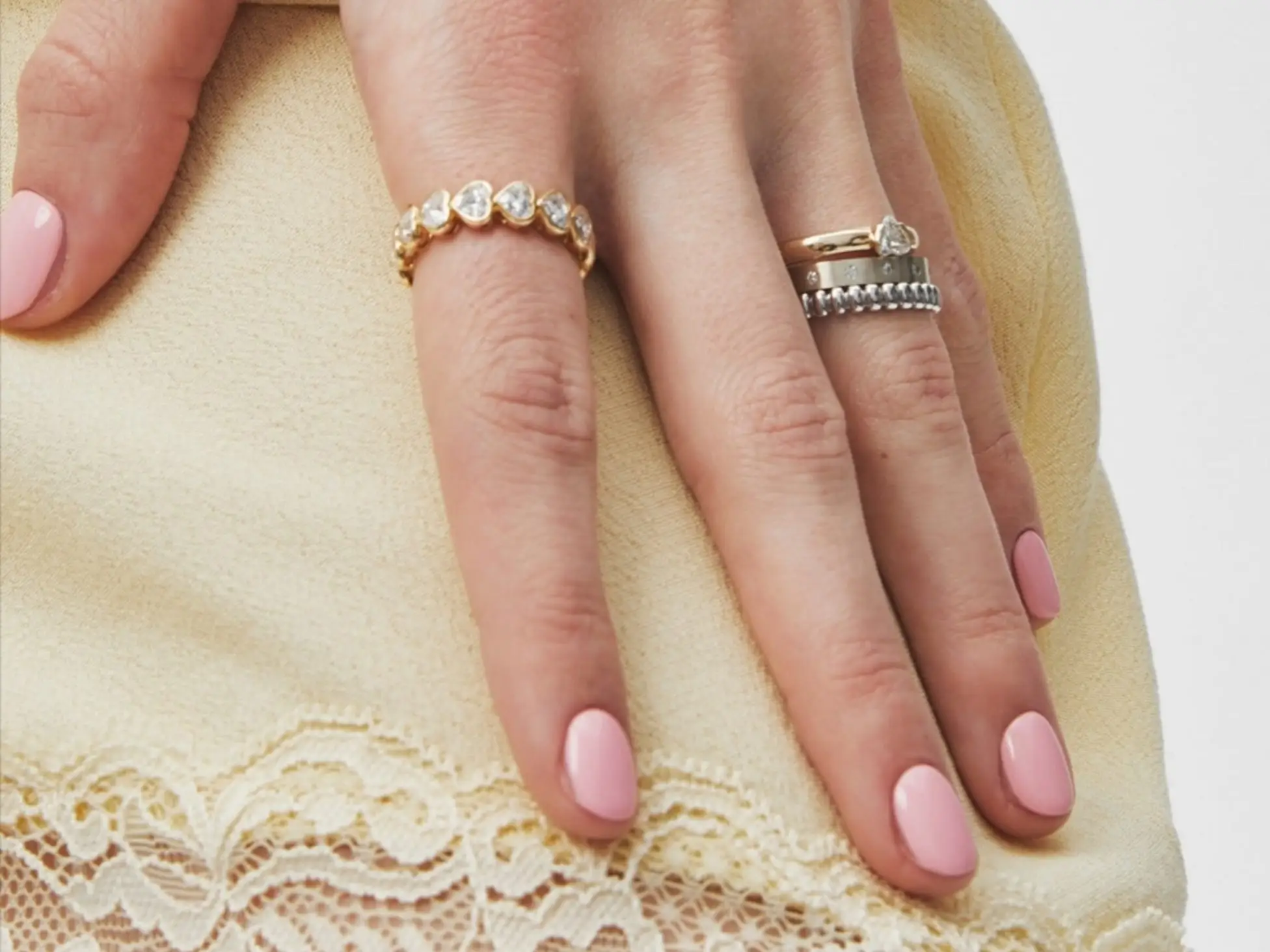 A hand wearing a stack of gold and silver rings.