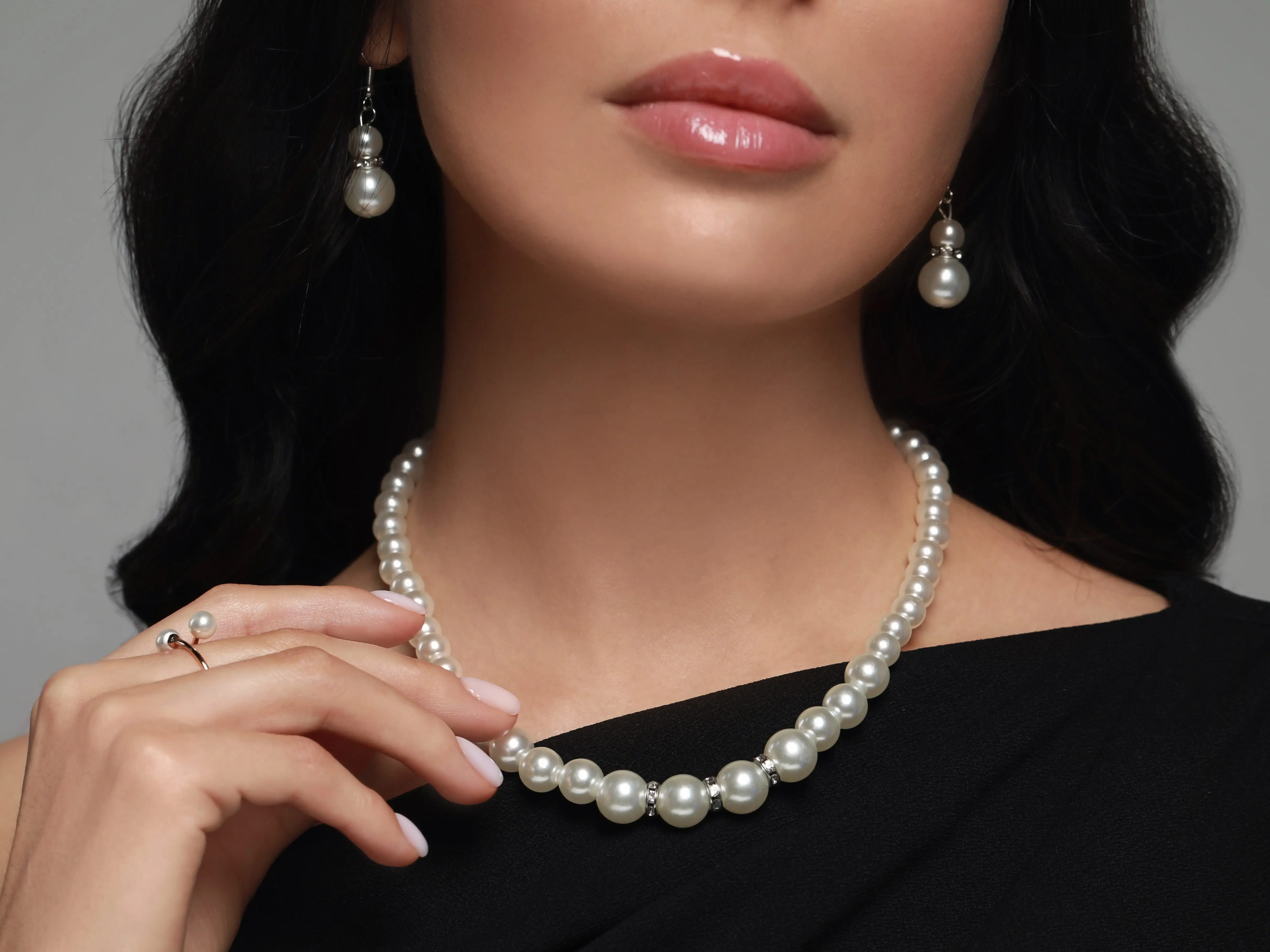 A woman wearing a chunky pearl necklace and pearl earrings.