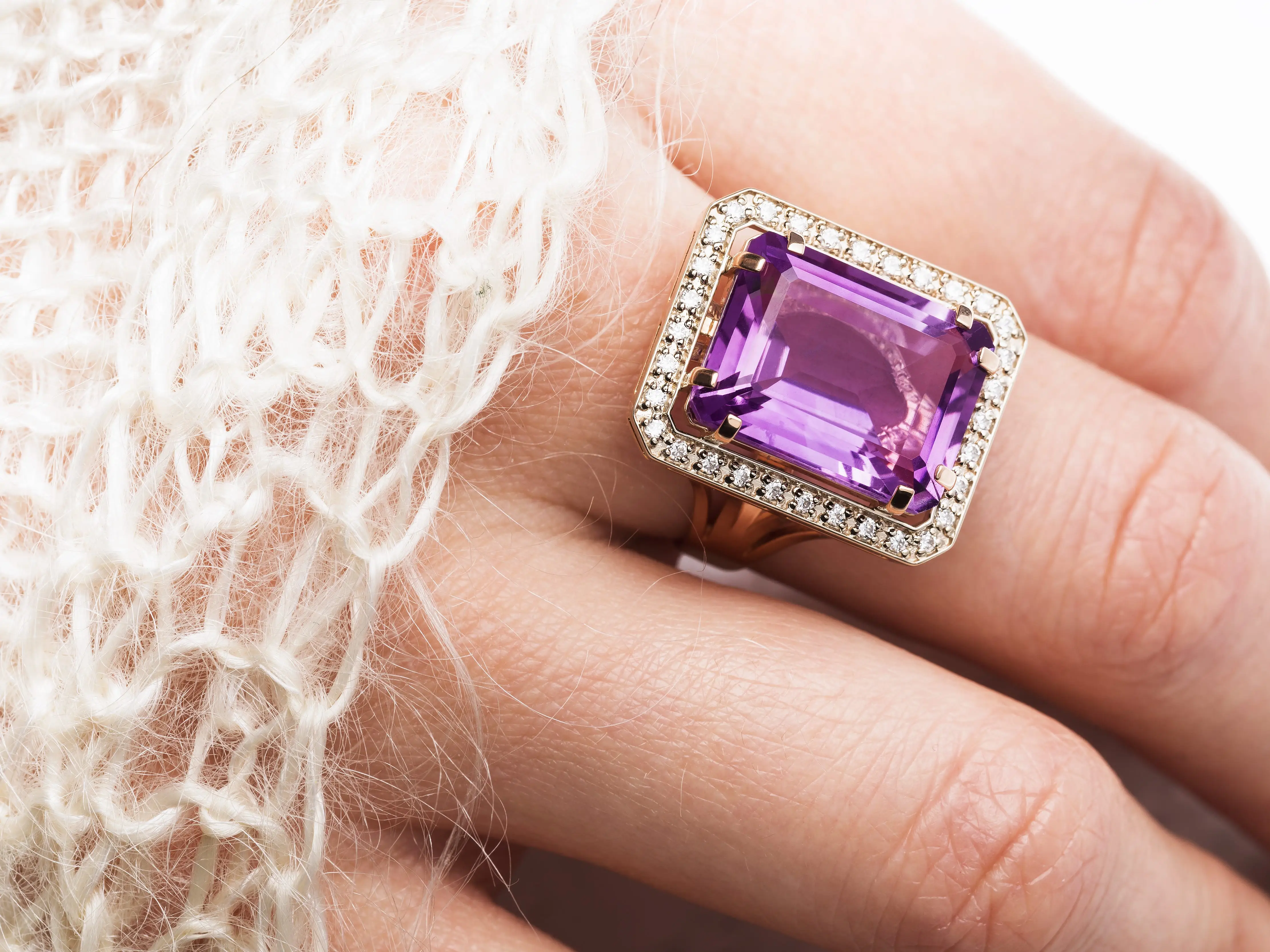 A close-up photo of a hand wearing an amethyst cocktail ring.