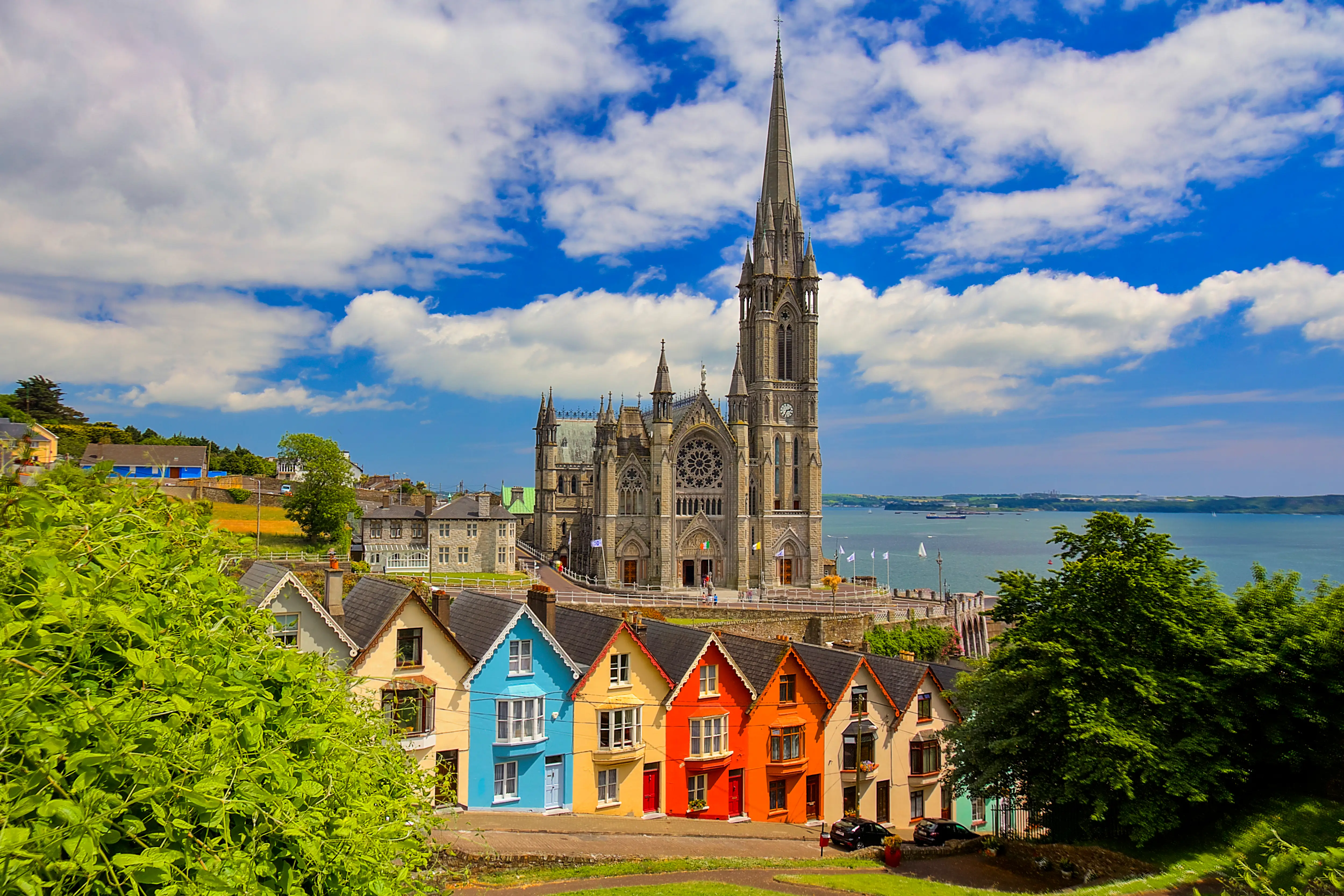 A cathedral in the background with a row of colorful homes in the foreground.