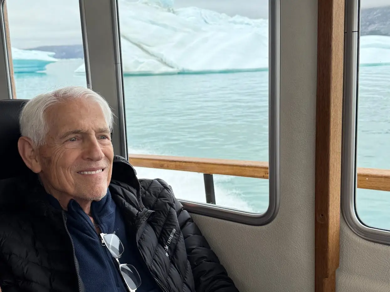 A man sitting inside a boat while looking at glaciers in Greenland.