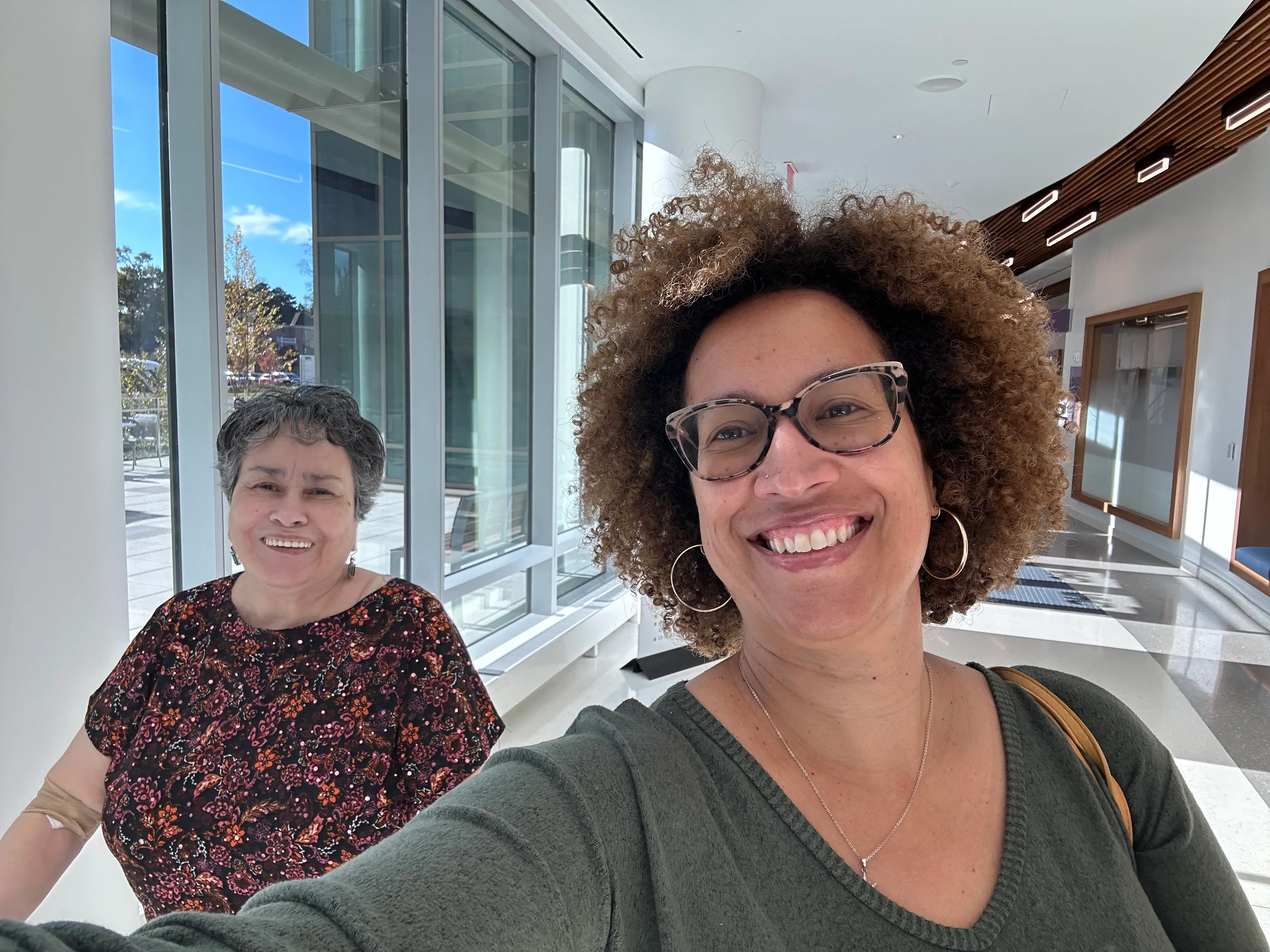 A selfie of a woman and her mom walking inside a care facility.