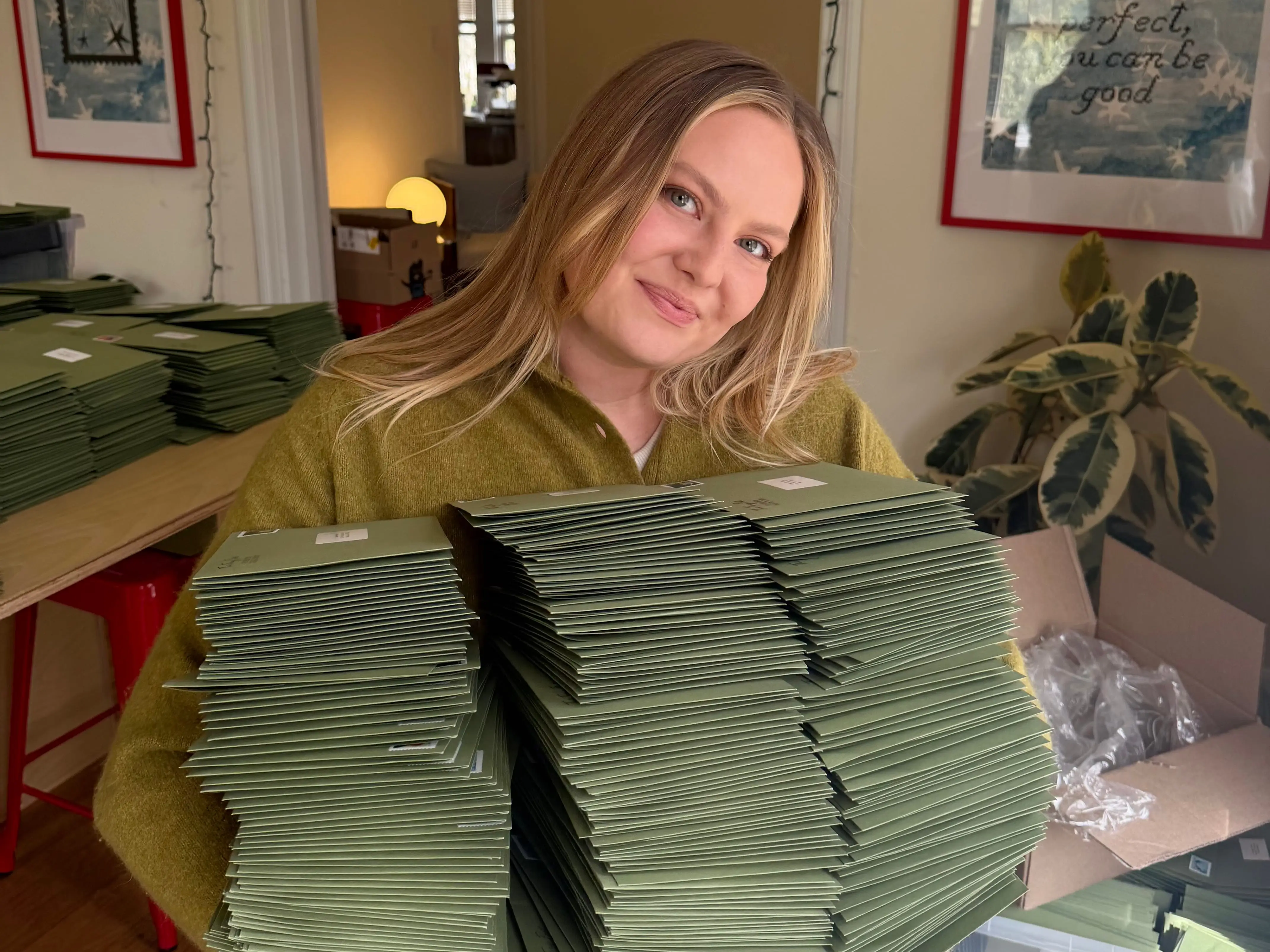 A woman holds huge piles of green envelopes